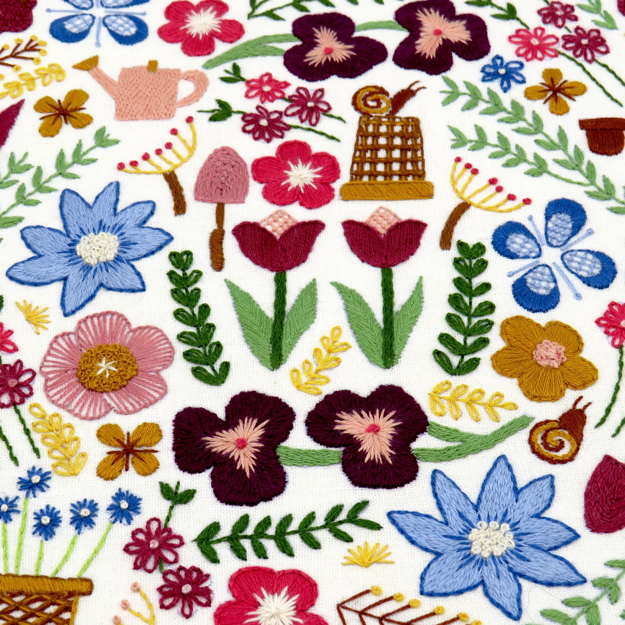 Embroidered pattern of flowers, plants, and a snail on a white background