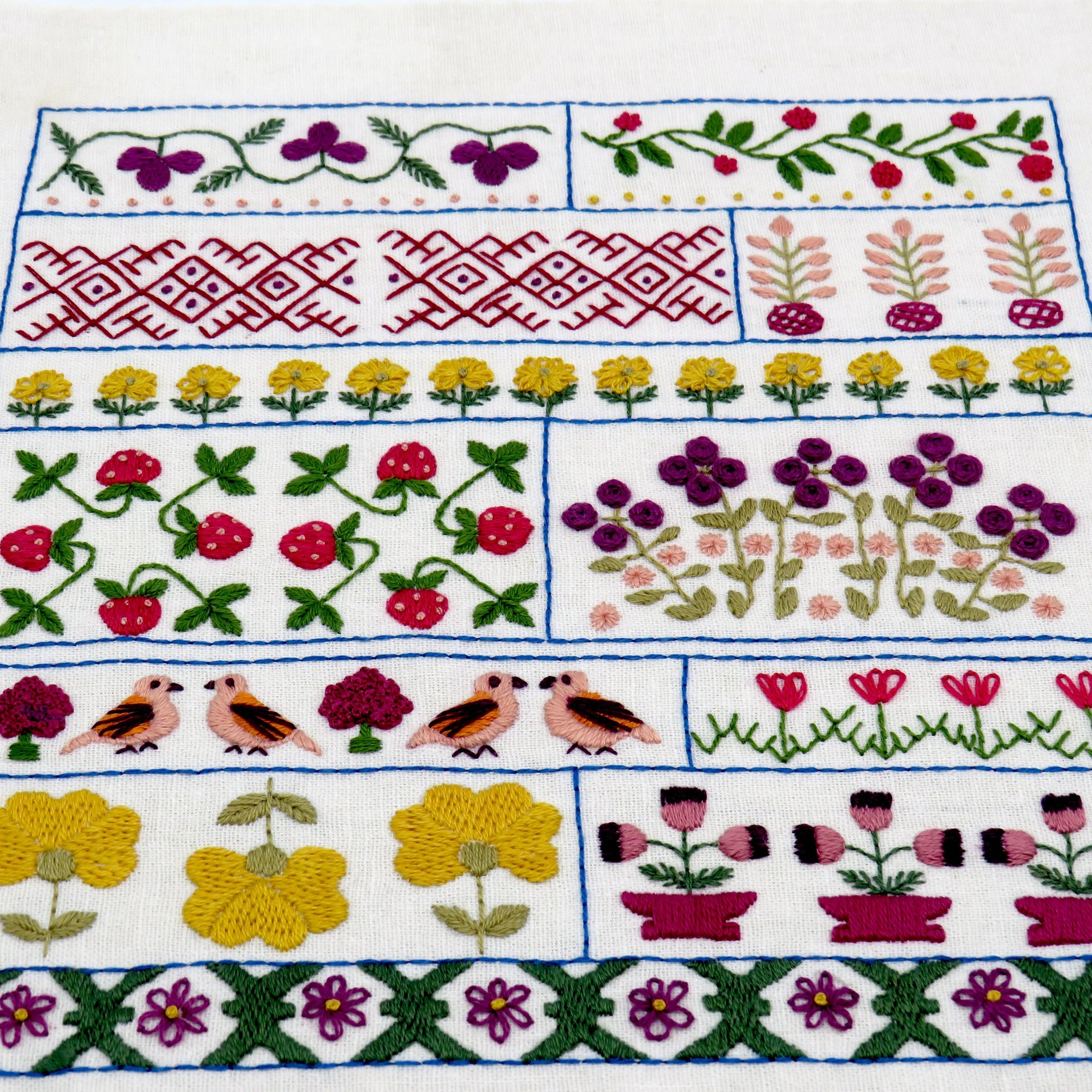 Embroidered fabric with floral, bird, and geometric patterns on a white background