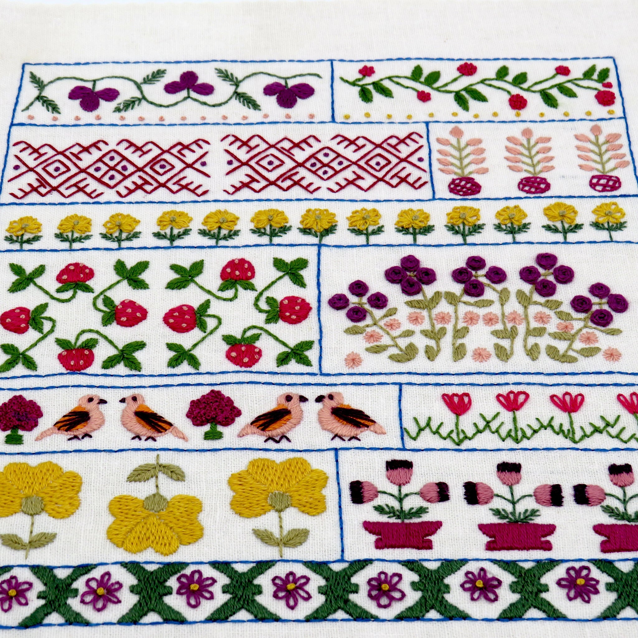 Embroidered fabric with floral, bird, and geometric patterns on a white background