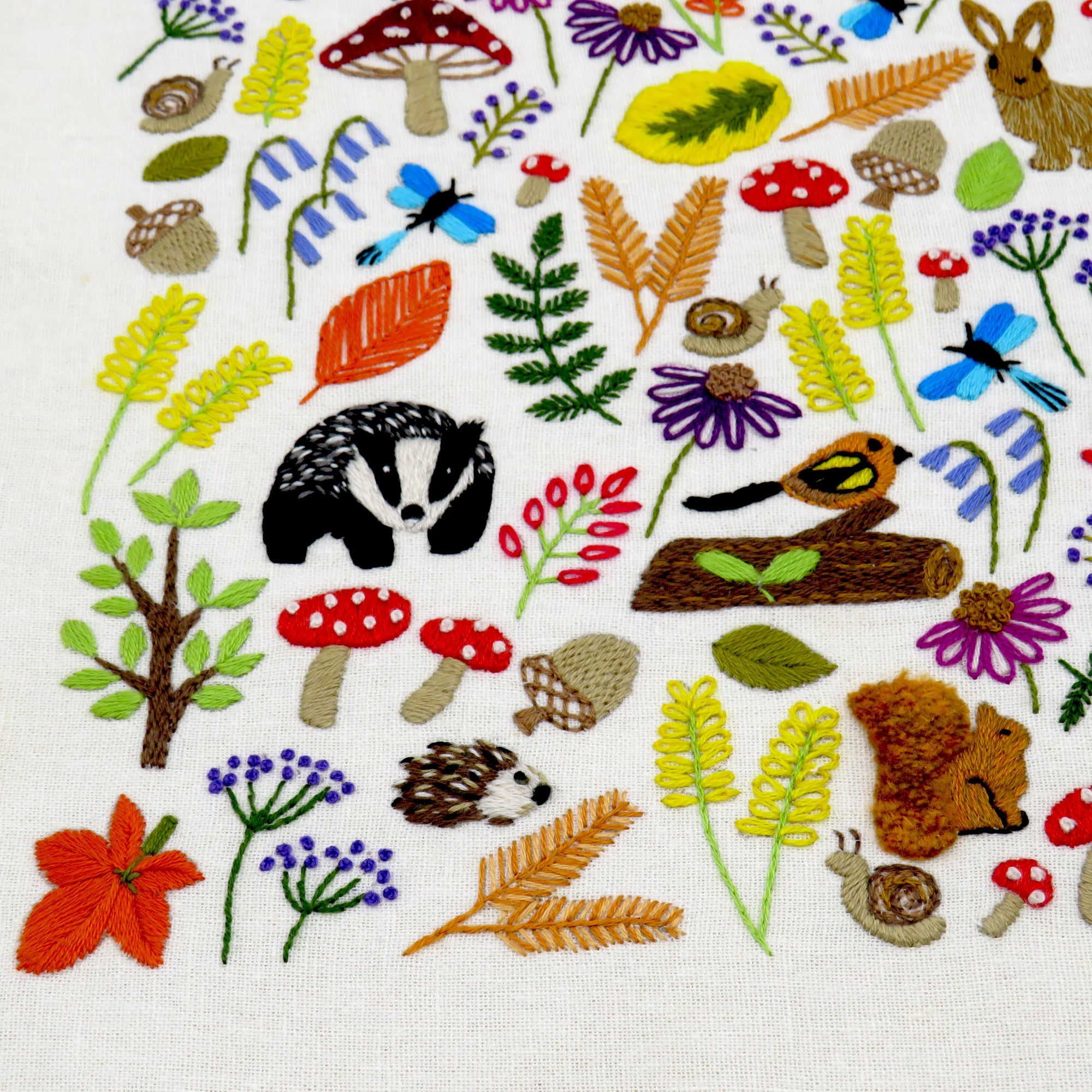 Embroidered pattern with animals, plants, and nature-themed elements on a white background