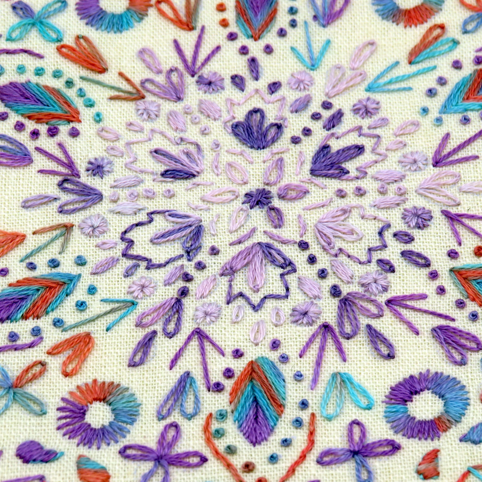 Colorful embroidered pattern on fabric with various shapes and colors.