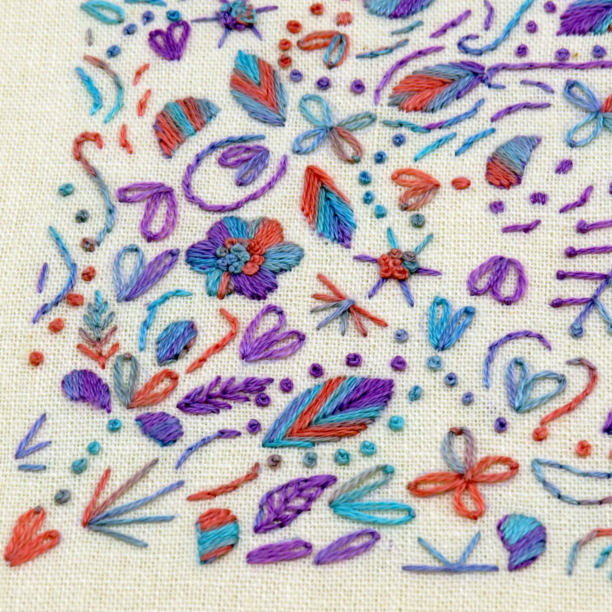 Colorful embroidered pattern on fabric with various floral and leaf designs.