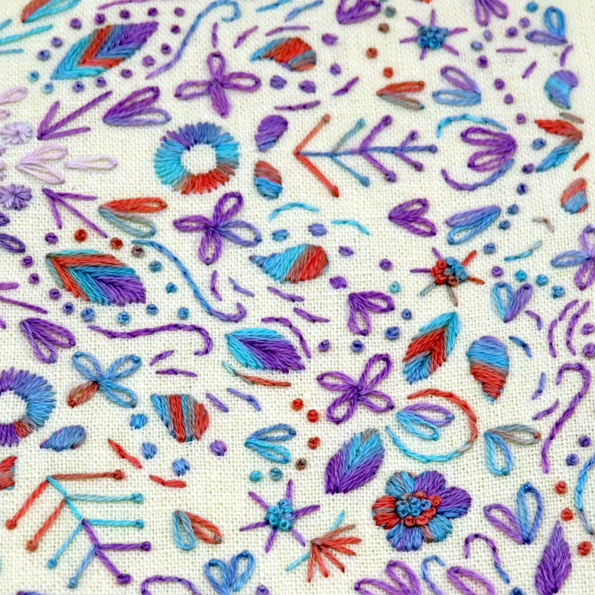 Colorful embroidered pattern on fabric with various shapes and colors.