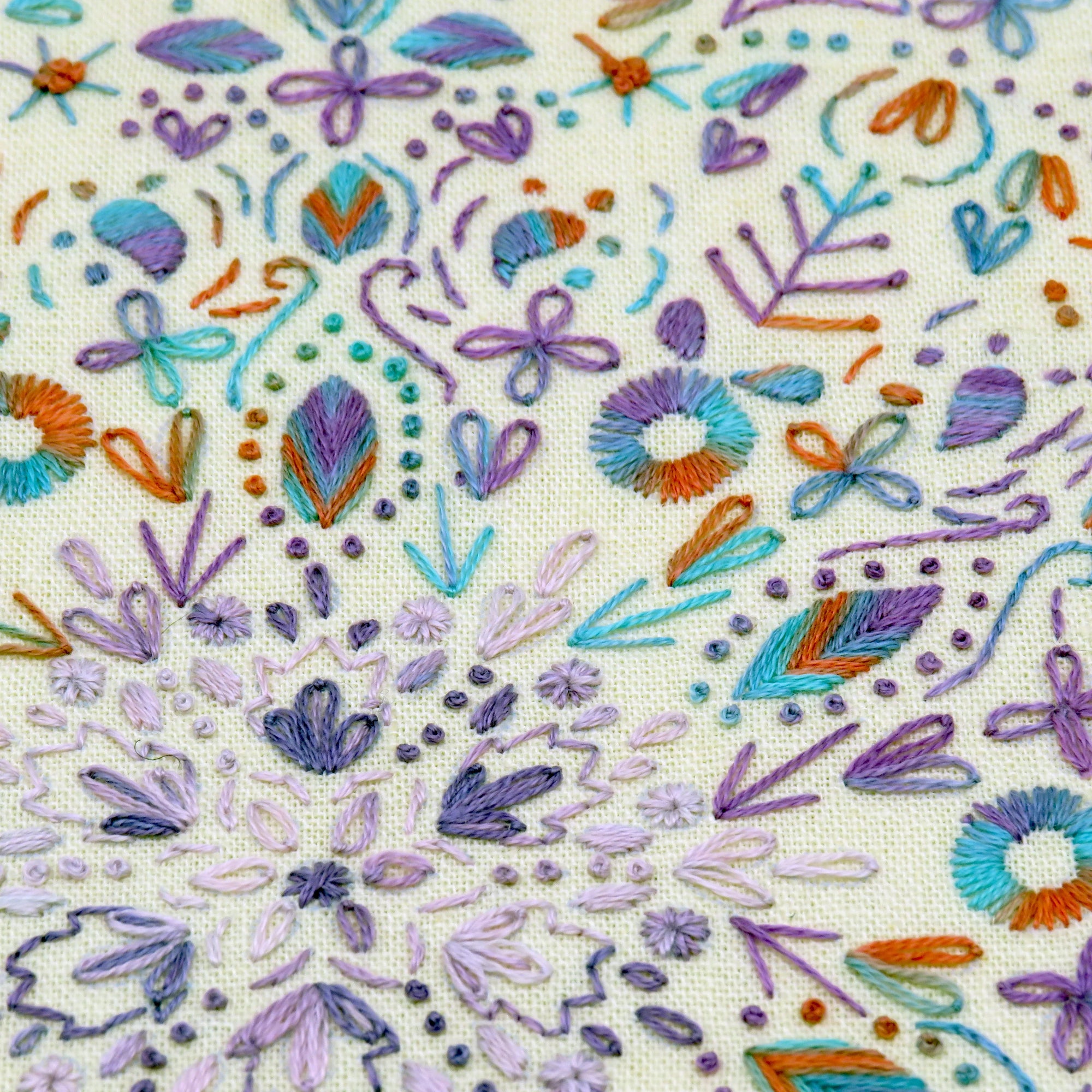 Embroidered pattern with colorful flowers and leaves on a beige fabric background