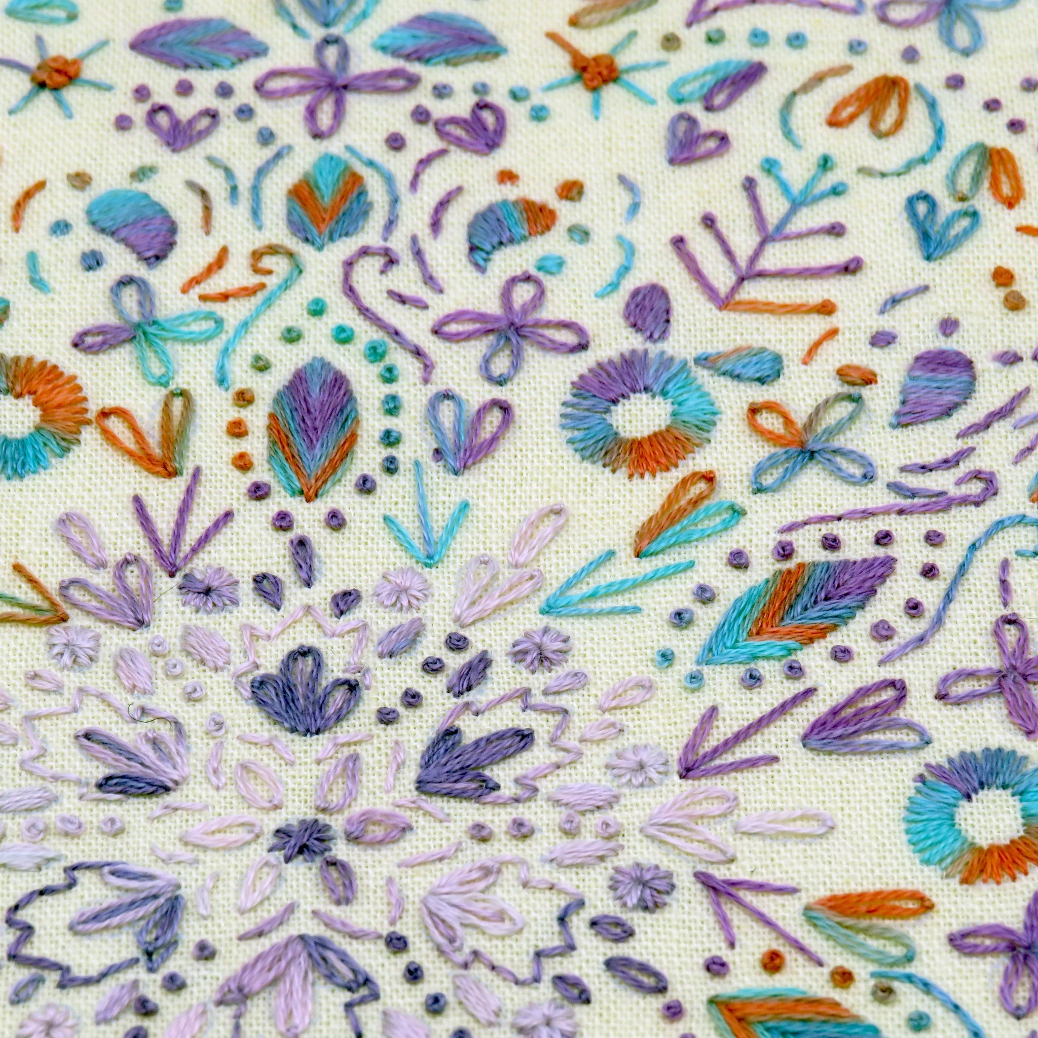 Embroidered pattern with colorful flowers and leaves on a beige fabric background