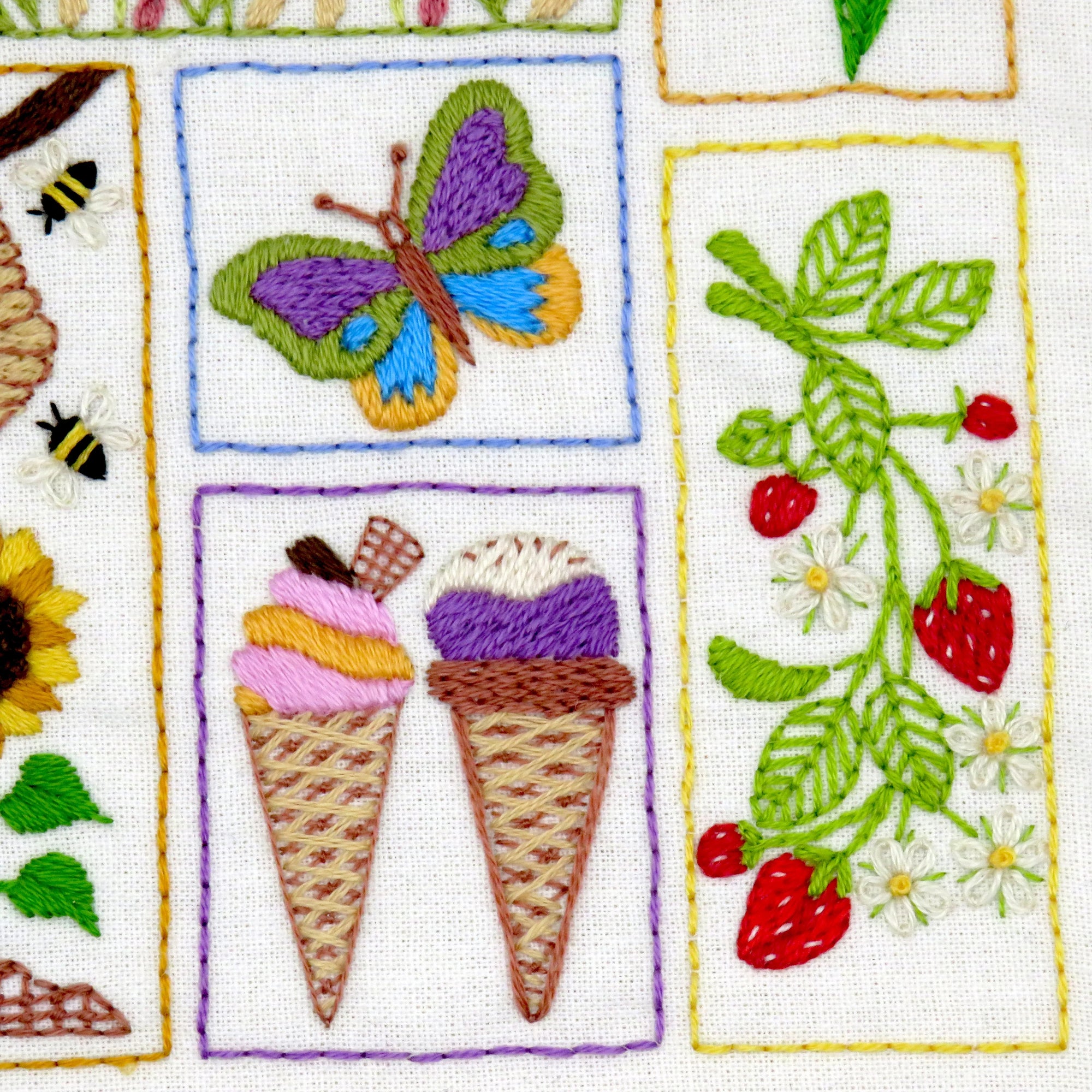 Embroidered patchwork with butterfly, ice cream cones, and strawberry design on a white background.