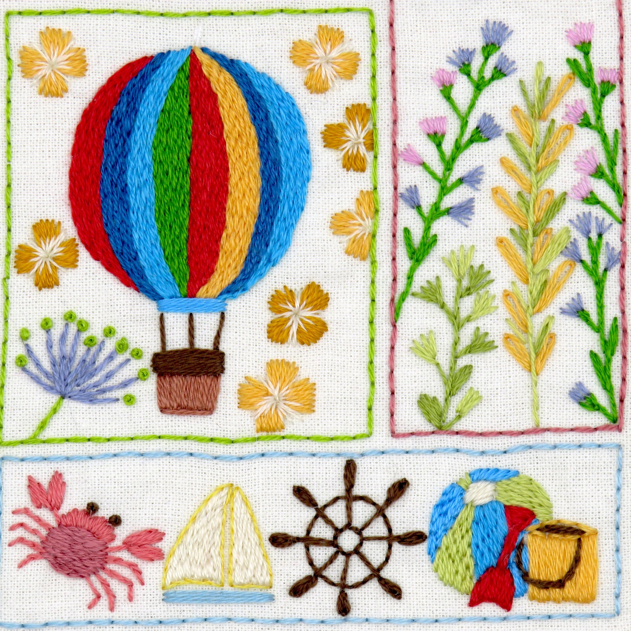 Embroidered design with hot air balloon, flowers, sailboat, crab, and wheel on a white background.