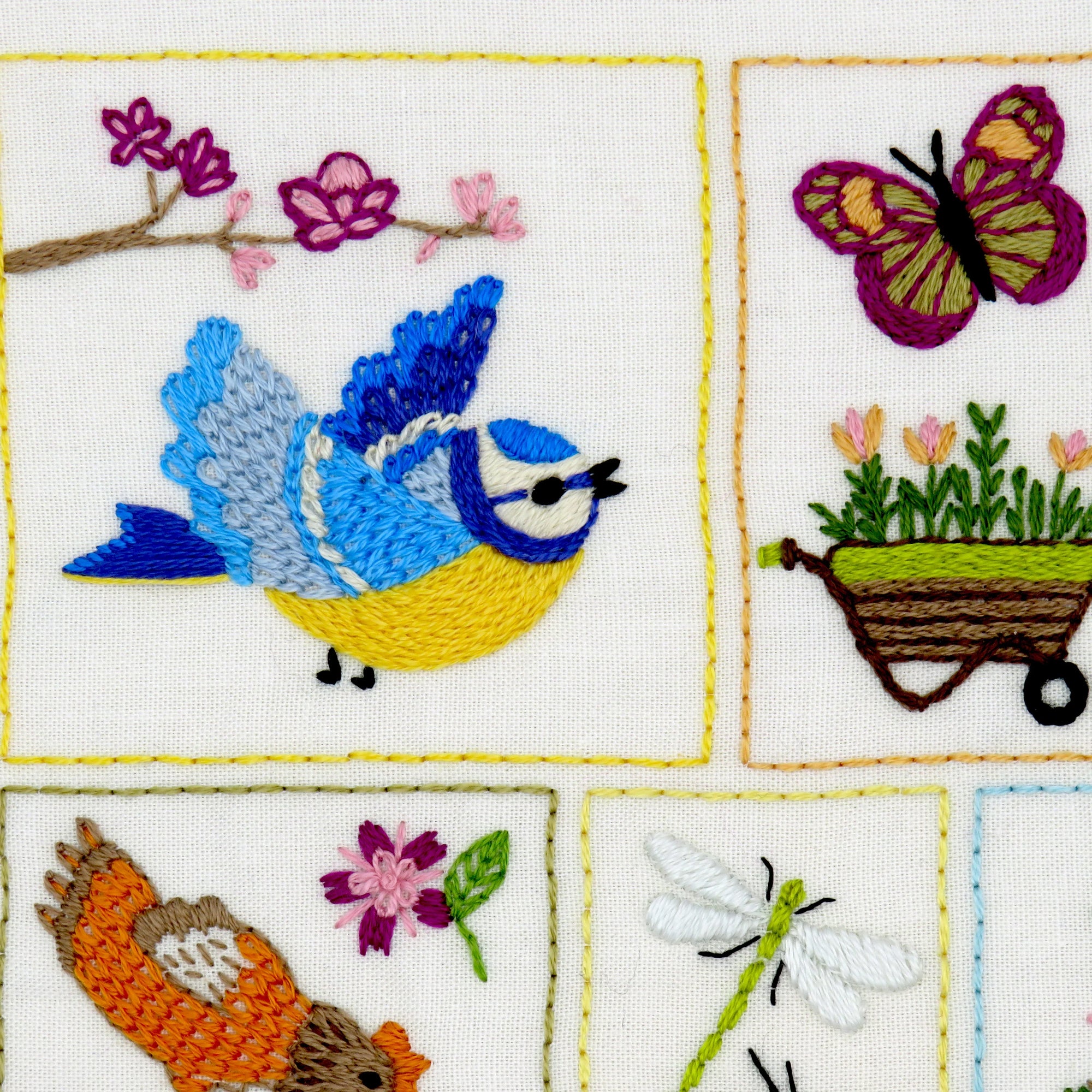 Embroidered panel with birds, flowers, and a butterfly on a white background