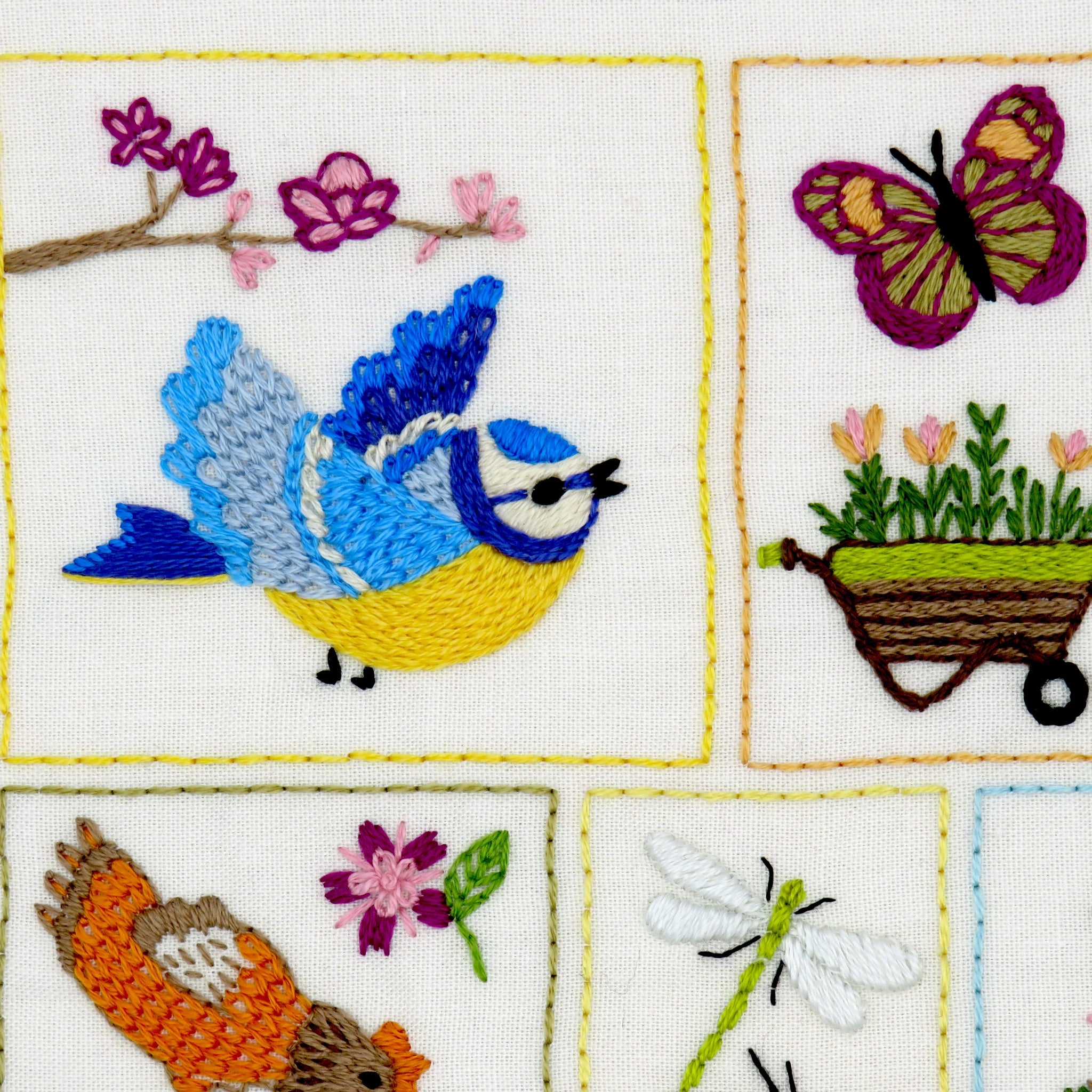 Embroidered panel with birds, flowers, and a butterfly on a white background