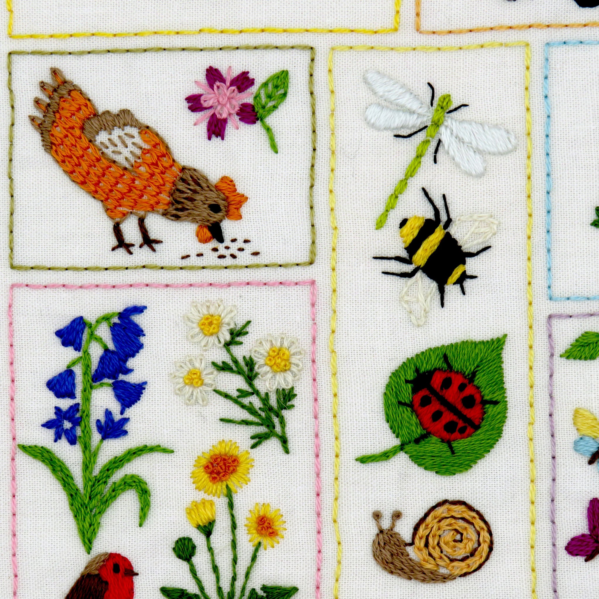 Embroidered patchwork with various nature-themed designs including birds, flowers, and insects.