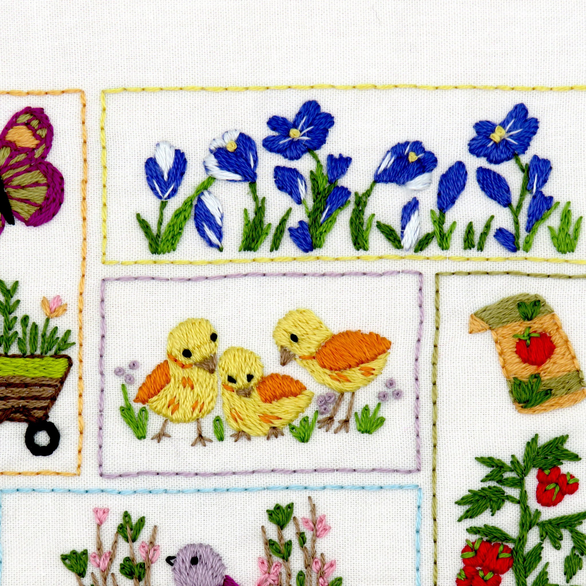Embroidered panel with birds, flowers, and a butterfly on a white background