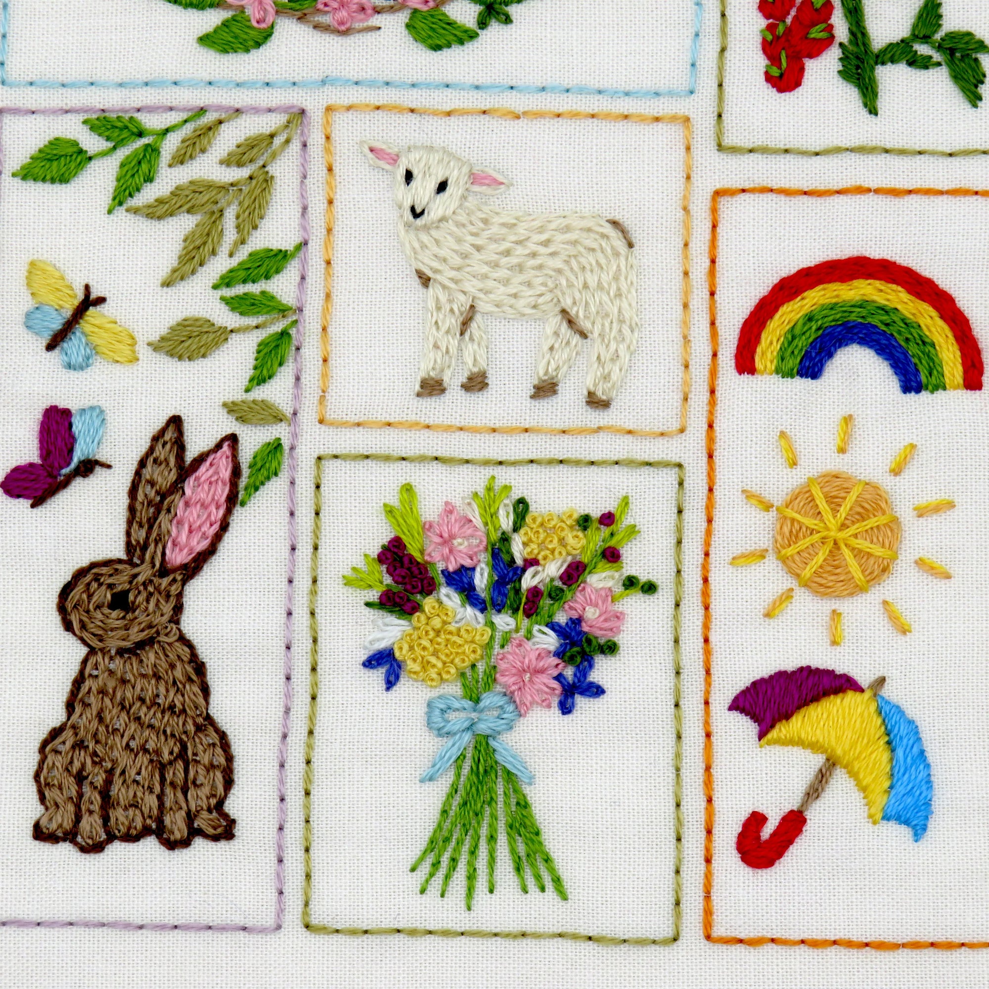 Embroidered patches with a rabbit, sheep, rainbow, sun, flowers, and umbrella on a white background.