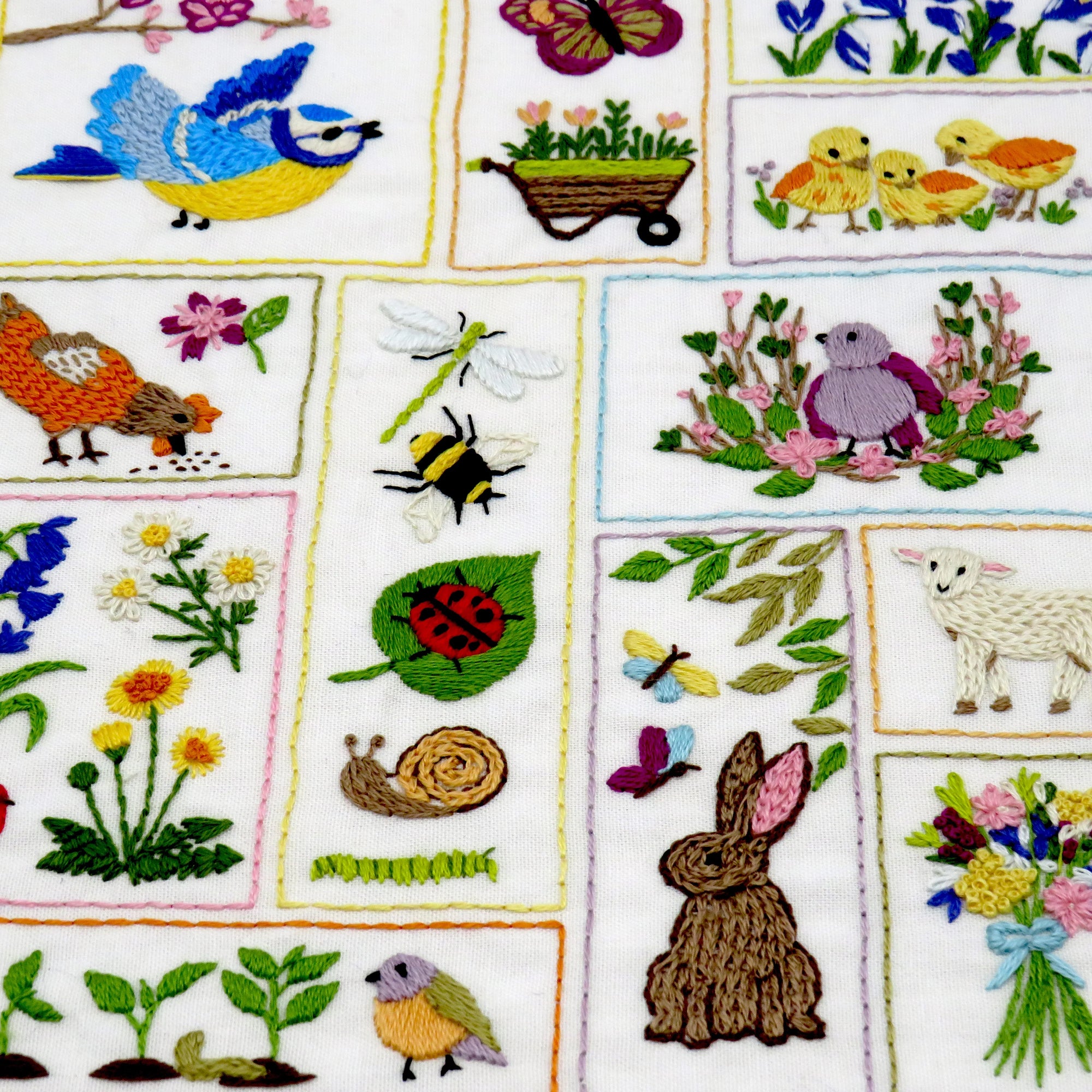 Embroidered fabric with various nature-themed designs including birds, flowers, and animals.