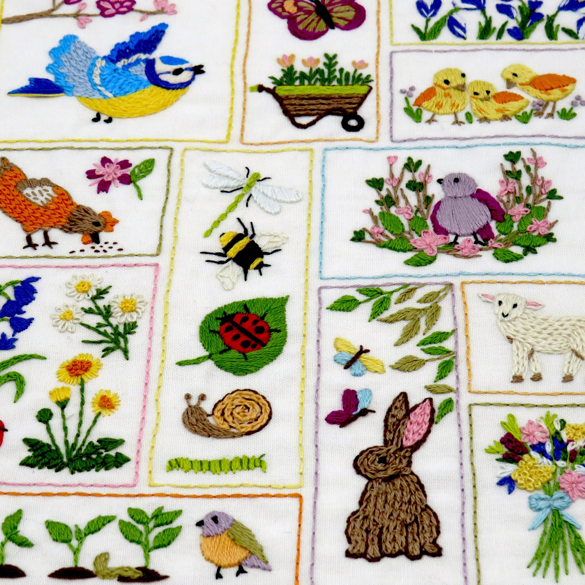 Embroidered fabric with various nature-themed designs including birds, flowers, and animals.