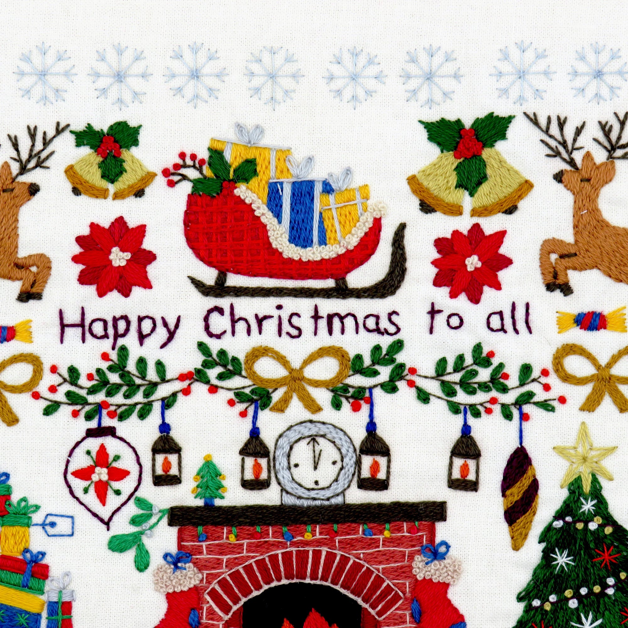 Embroidered Christmas design with a fireplace, sleigh, and festive elements on a white background.