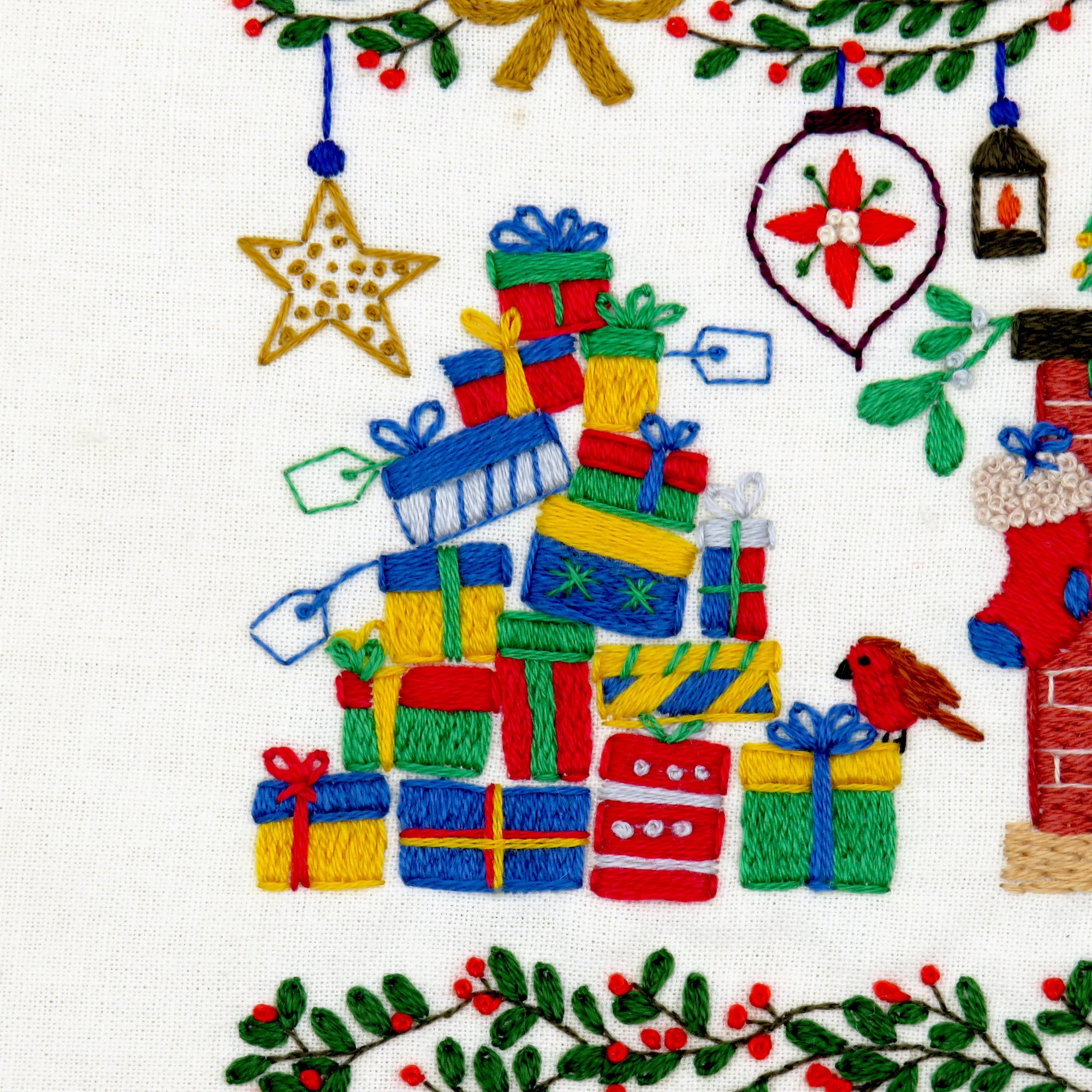 Embroidered design of Christmas presents, a star, and other festive elements on fabric.