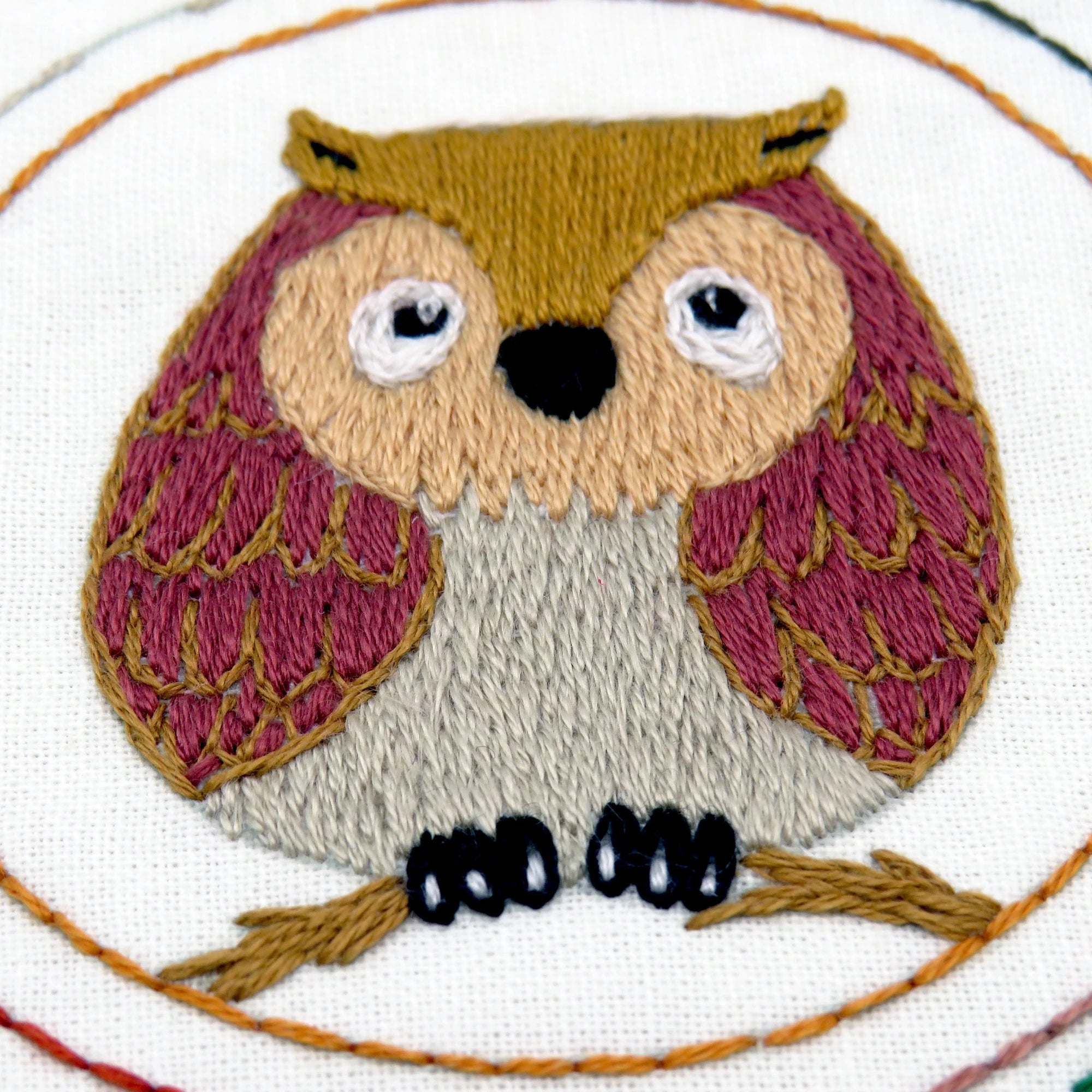 Embroidered owl design on fabric with a circular border.