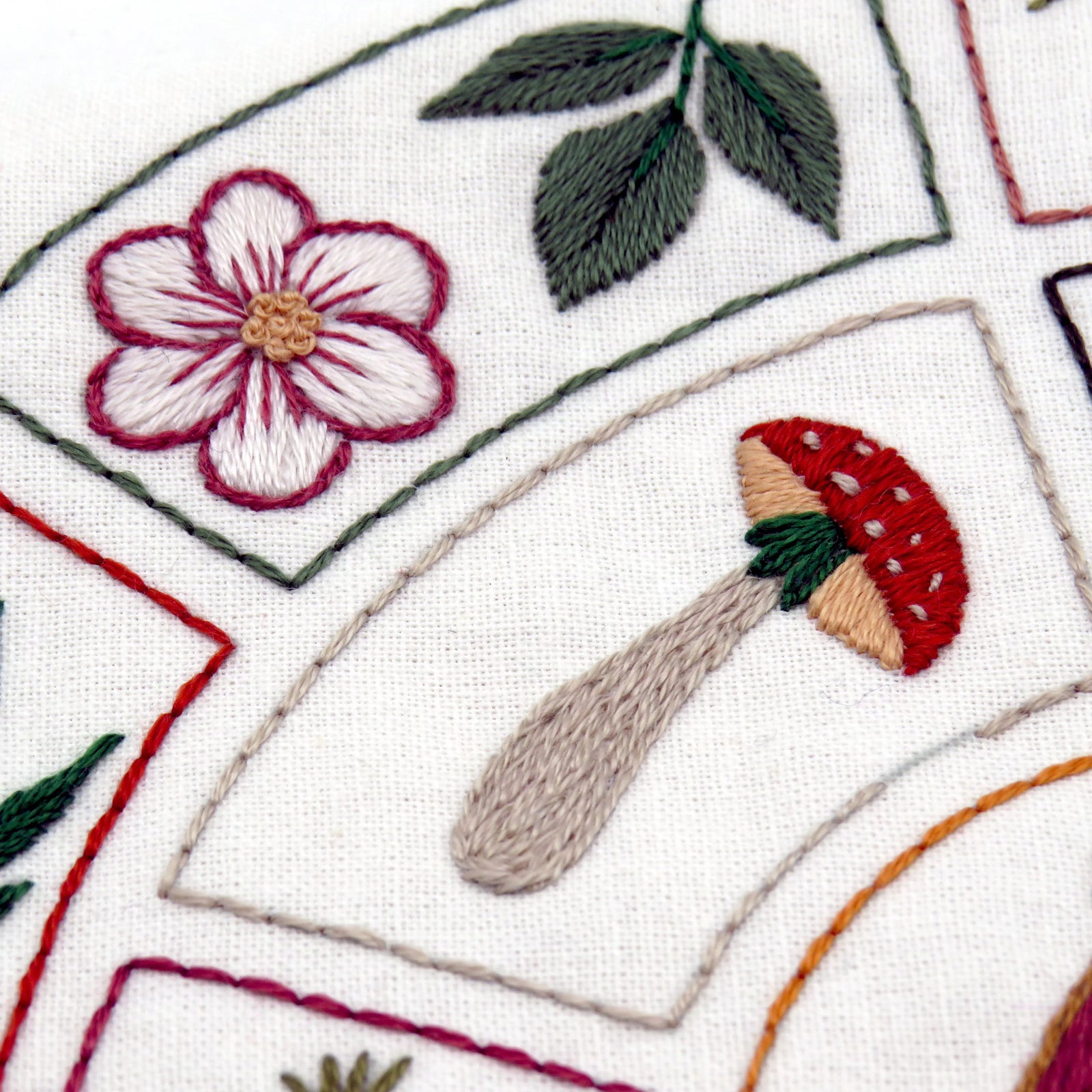 Embroidered design with a flower and mushroom on a white background
