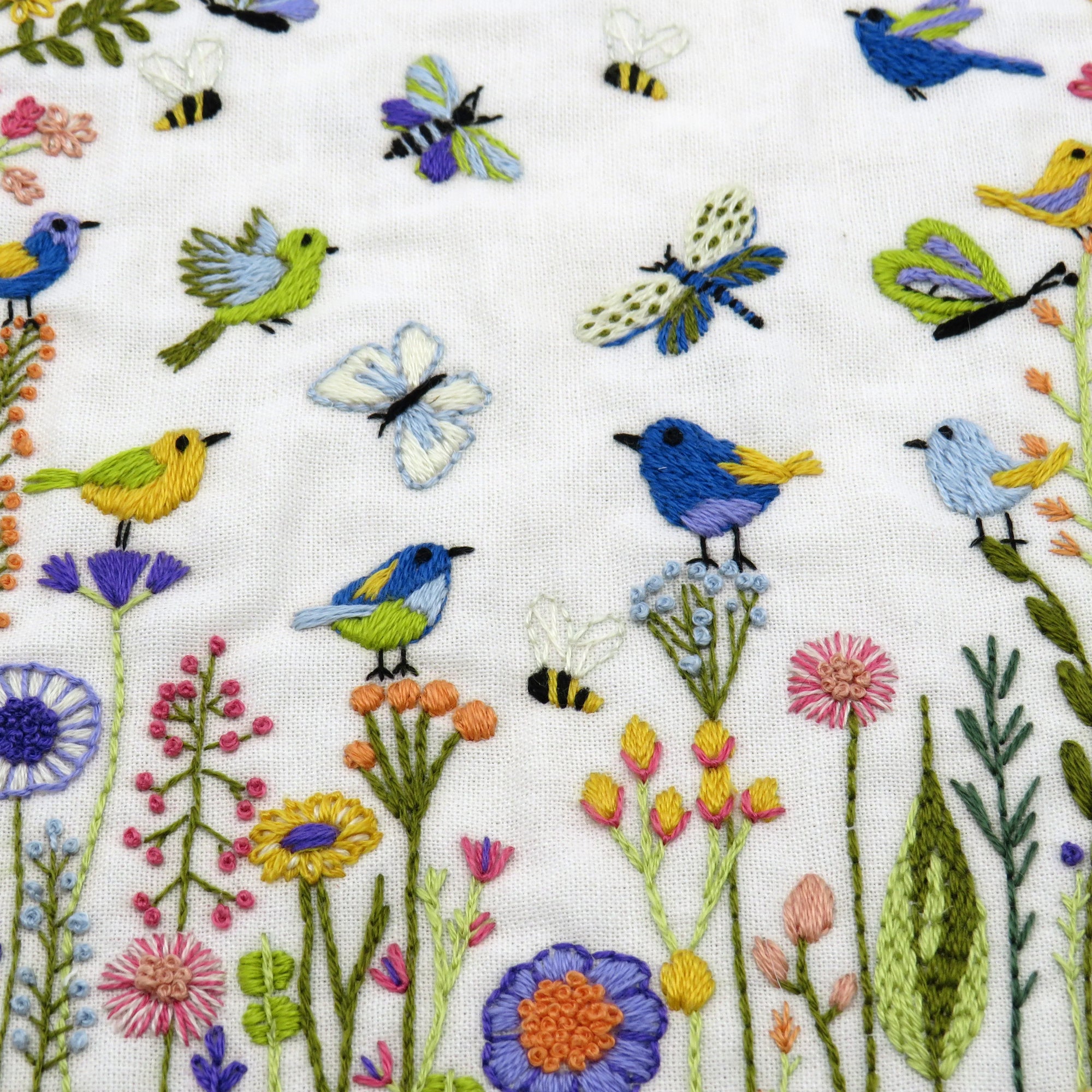 Embroidered pattern of birds, butterflies, and flowers on a white background