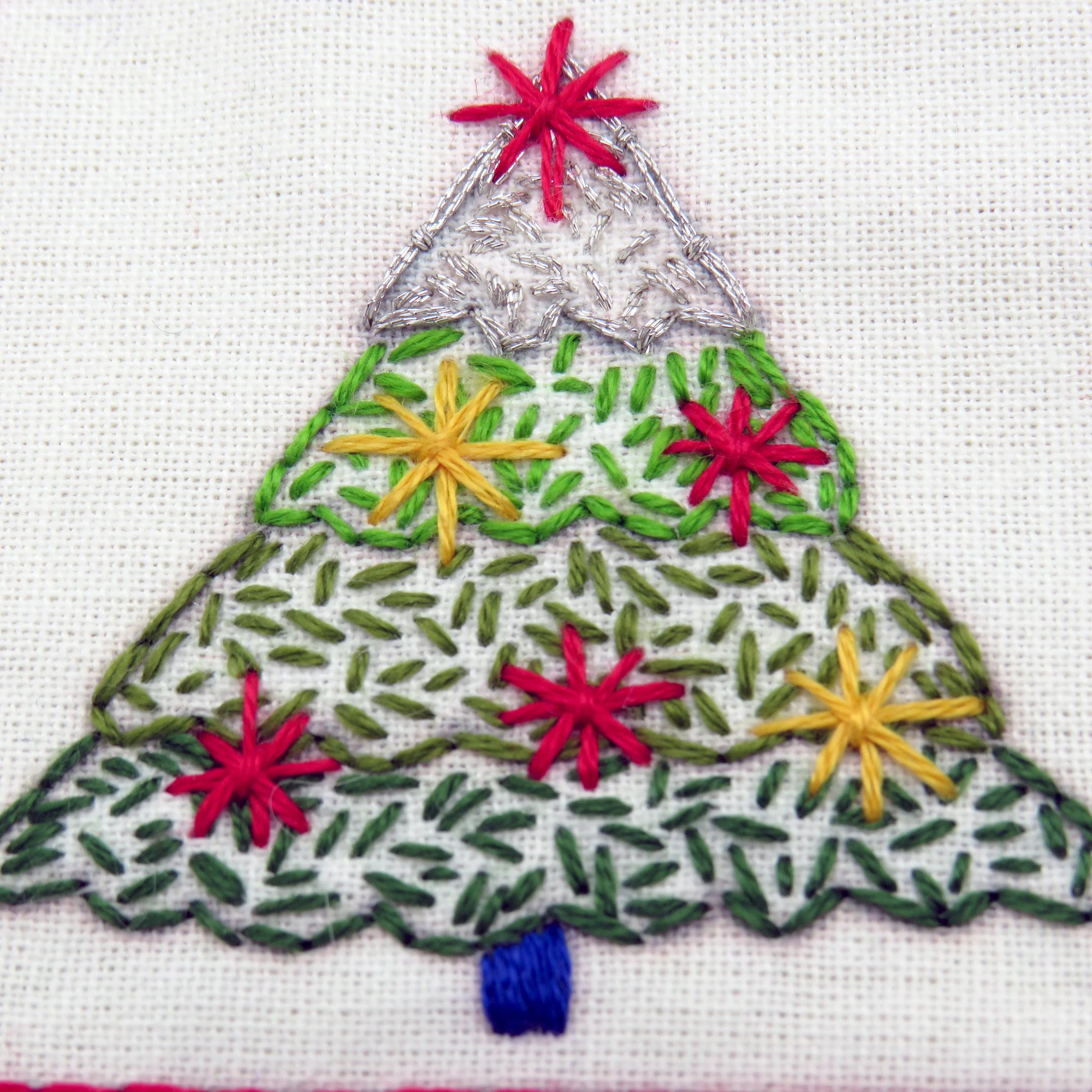 Embroidered Christmas tree design with colorful stars on a white background