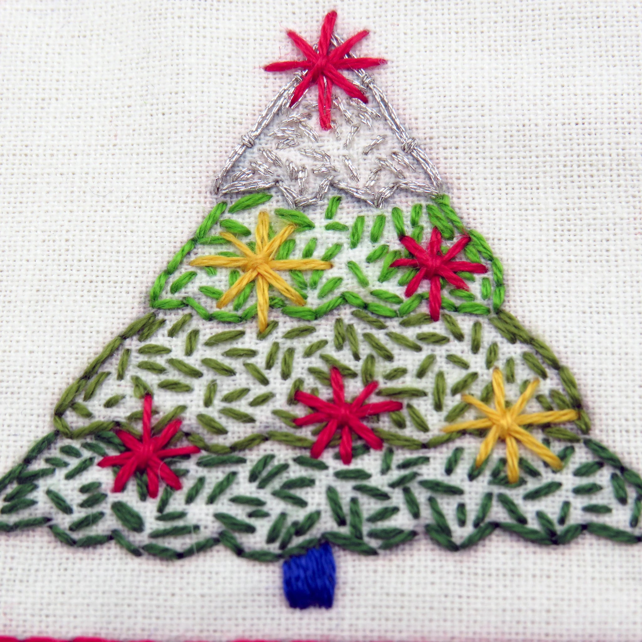 Embroidered Christmas tree design with colorful stars on a white background
