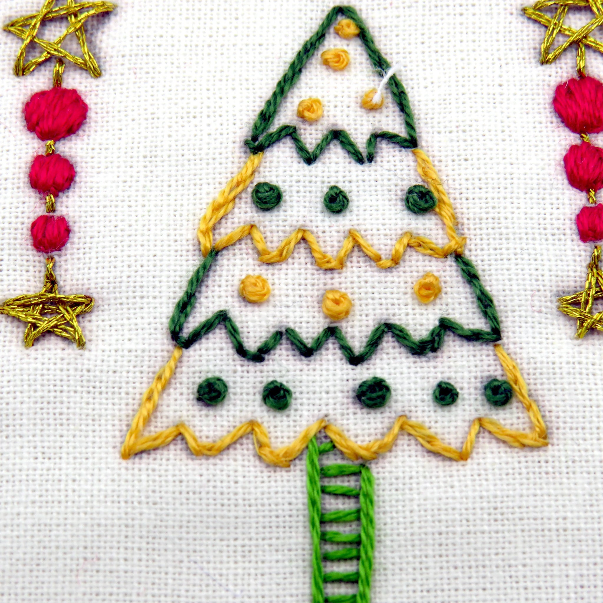Embroidered Christmas tree design with stars and baubles on a white background