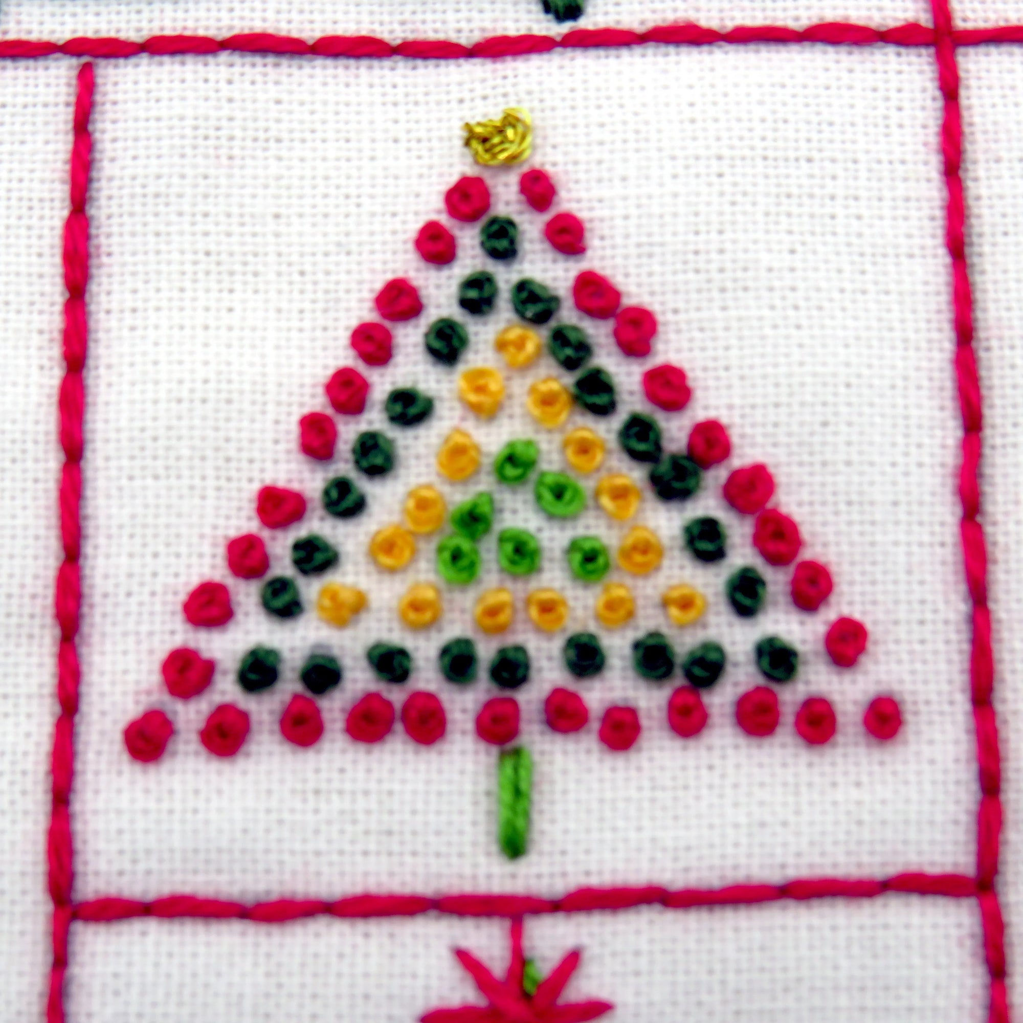 Embroidered Christmas tree design on fabric with red border