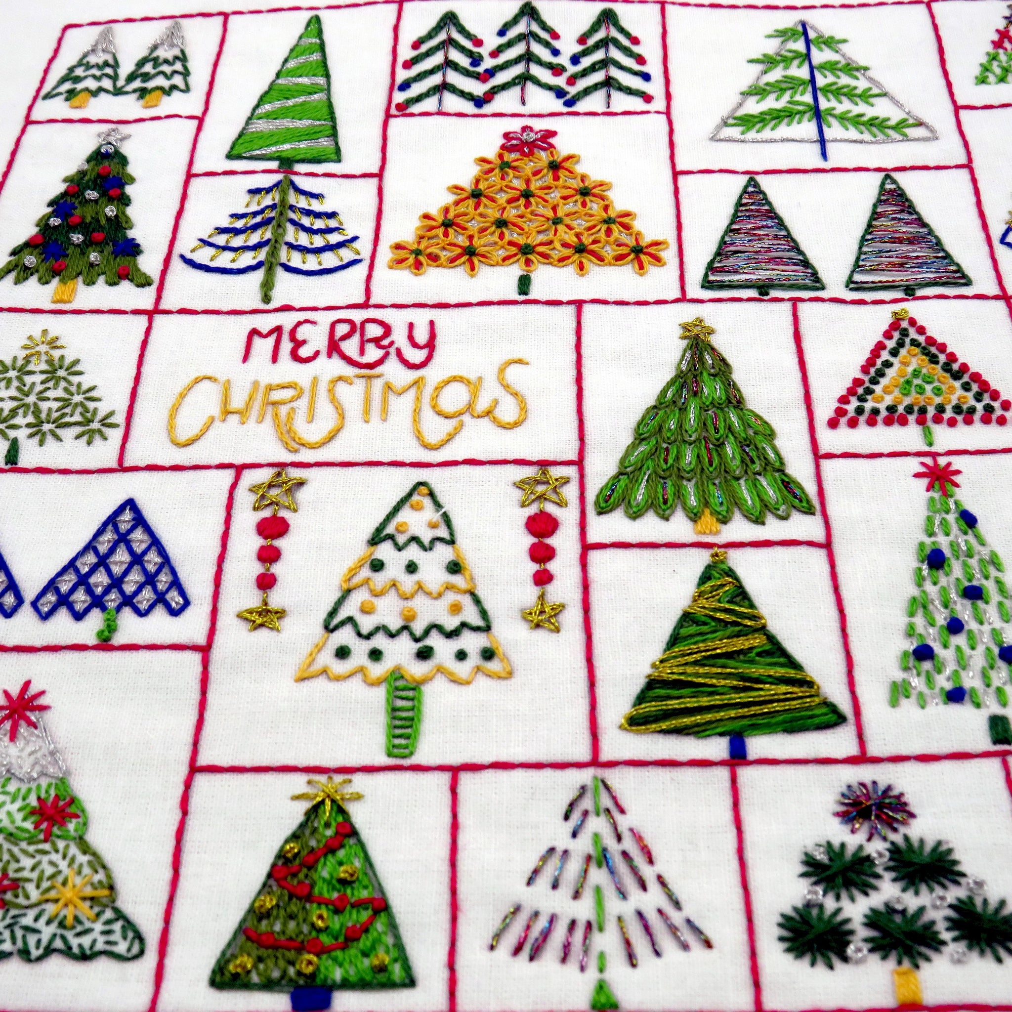 Embroidered Christmas trees on fabric with 'Merry Christmas' text.