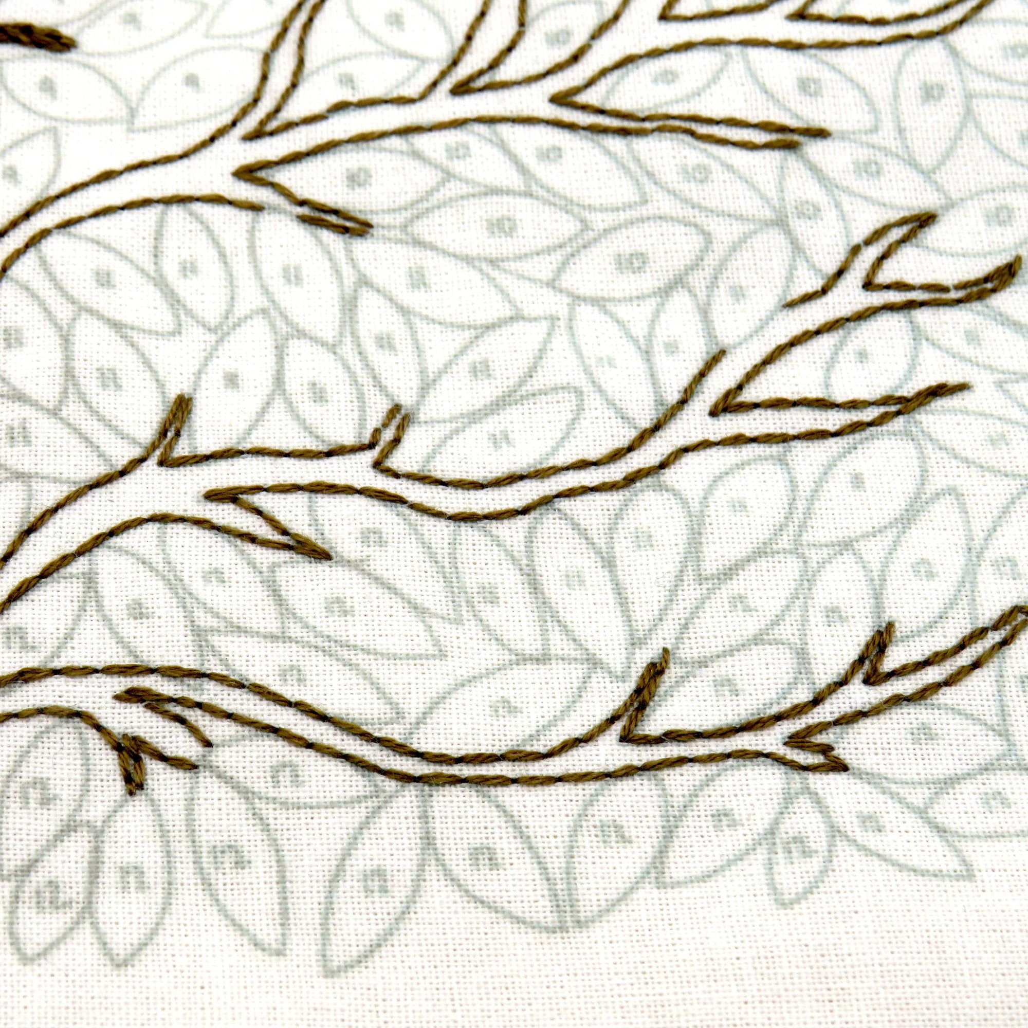 Embroidered pattern of leaves and branches on fabric