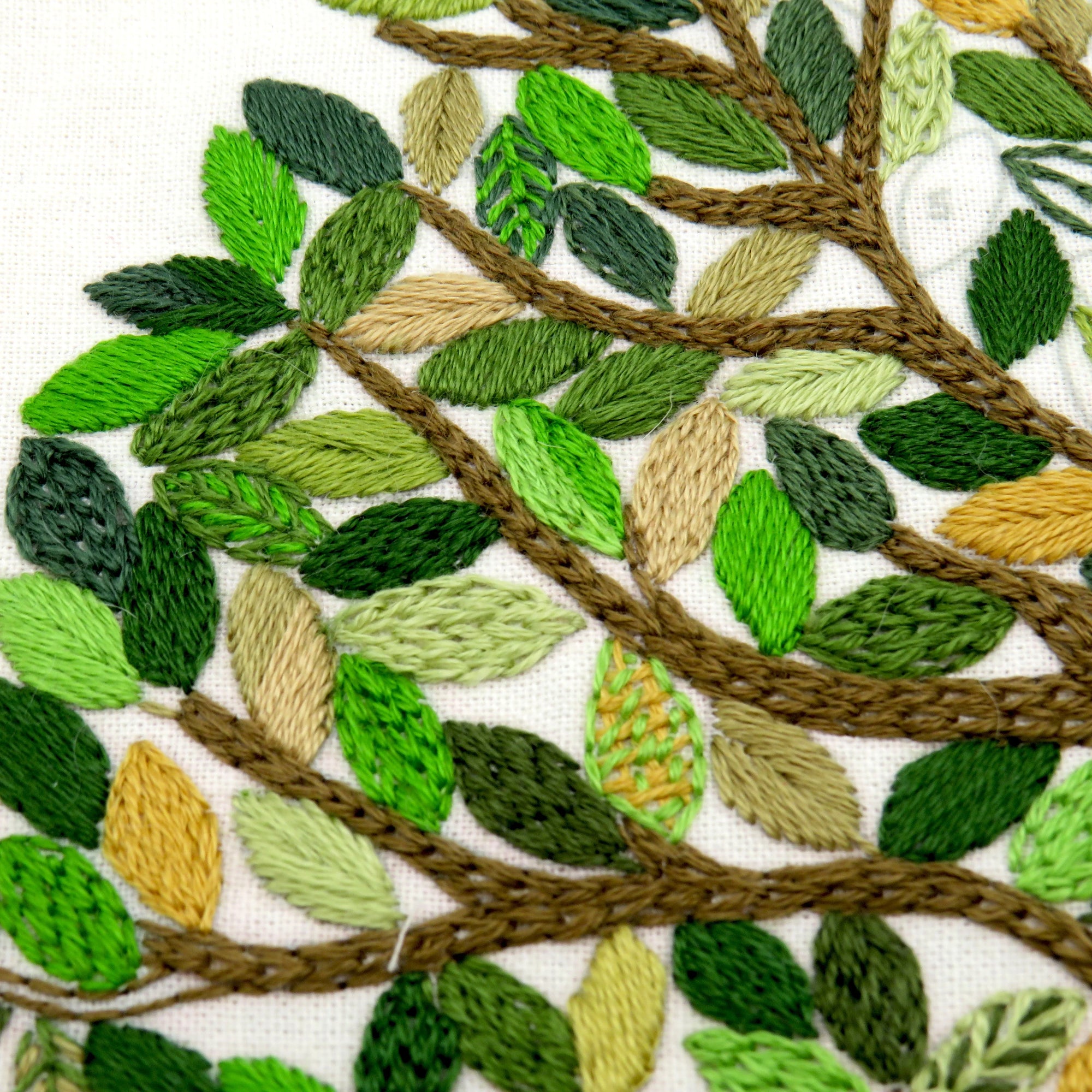 Embroidered design of leaves and branches on a white background
