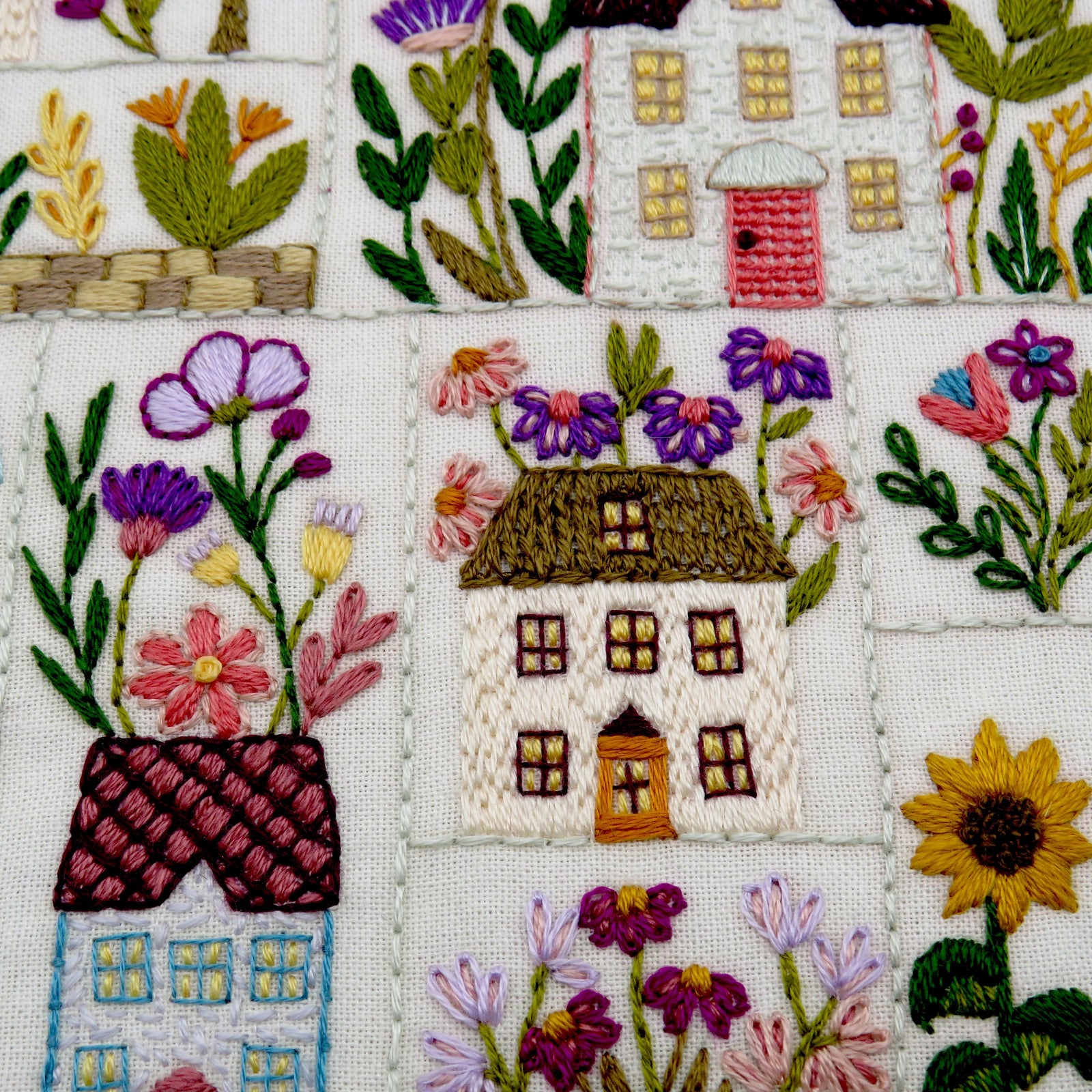 Embroidered scene with houses and flowers on fabric