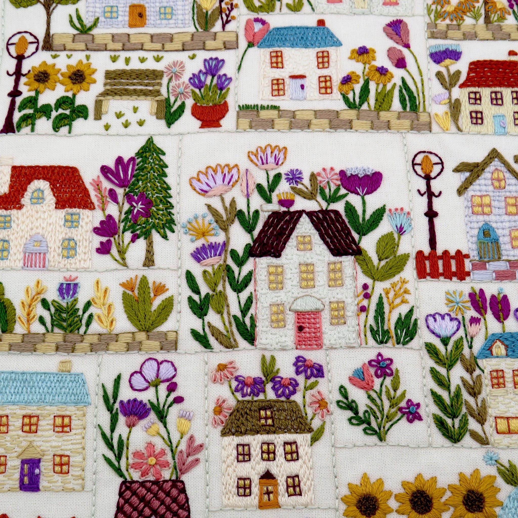 Embroidered pattern of houses and flowers on a white background