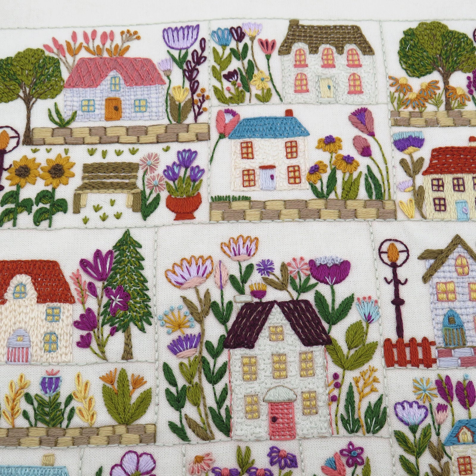 Embroidered pattern of houses and flowers on a white background