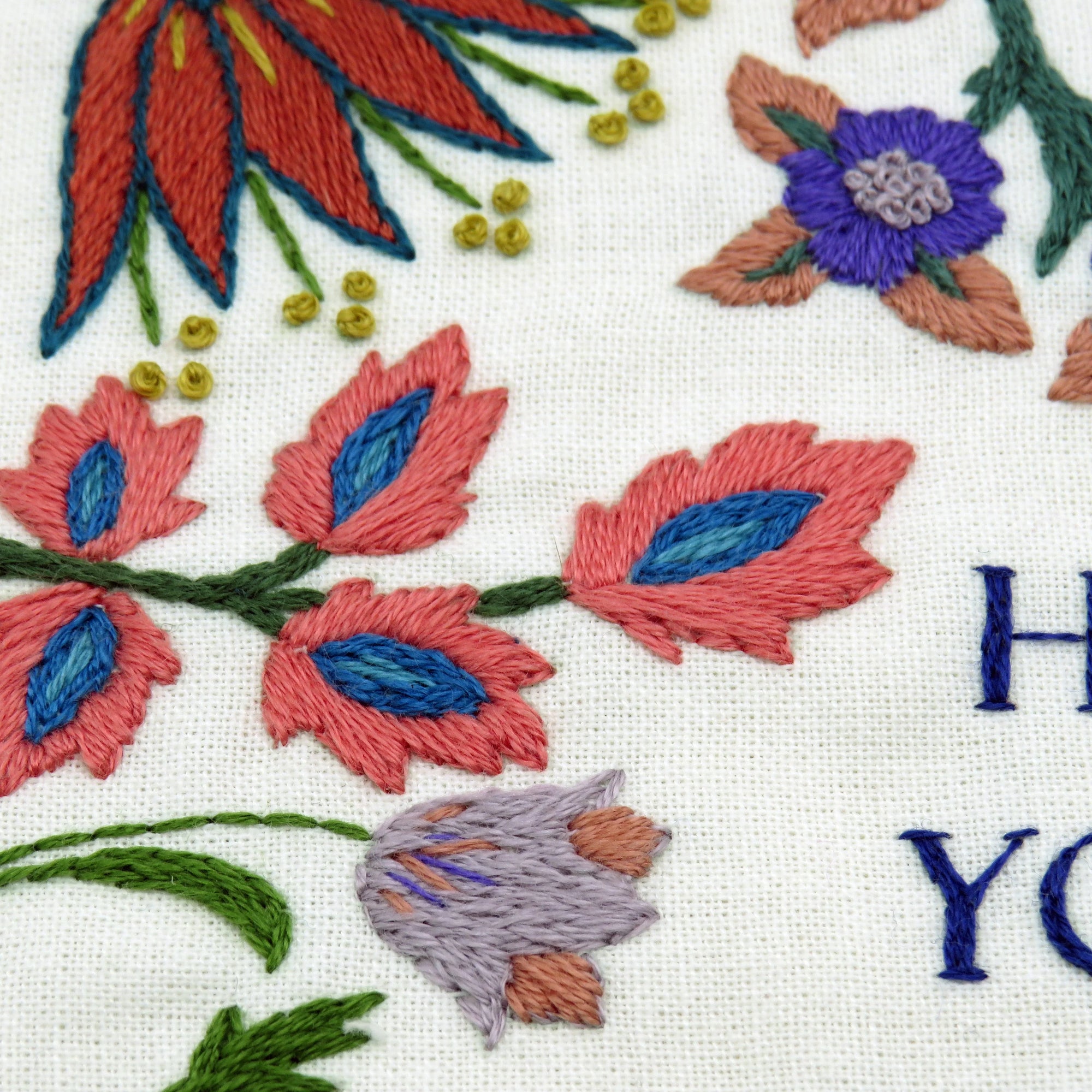 Embroidered floral design with colorful flowers on a white fabric background.