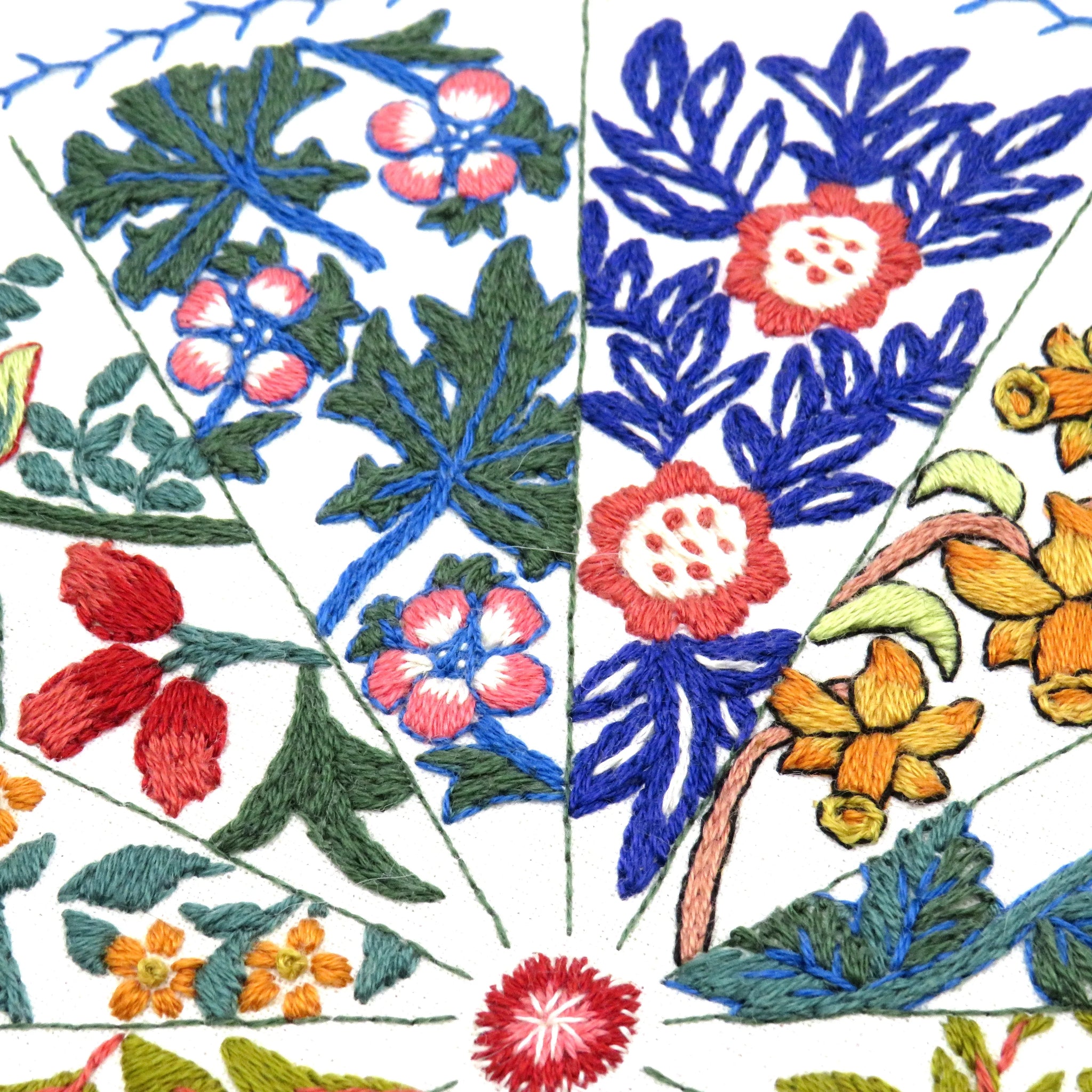 Embroidered floral pattern with red, blue, green, and orange colors on a white background.