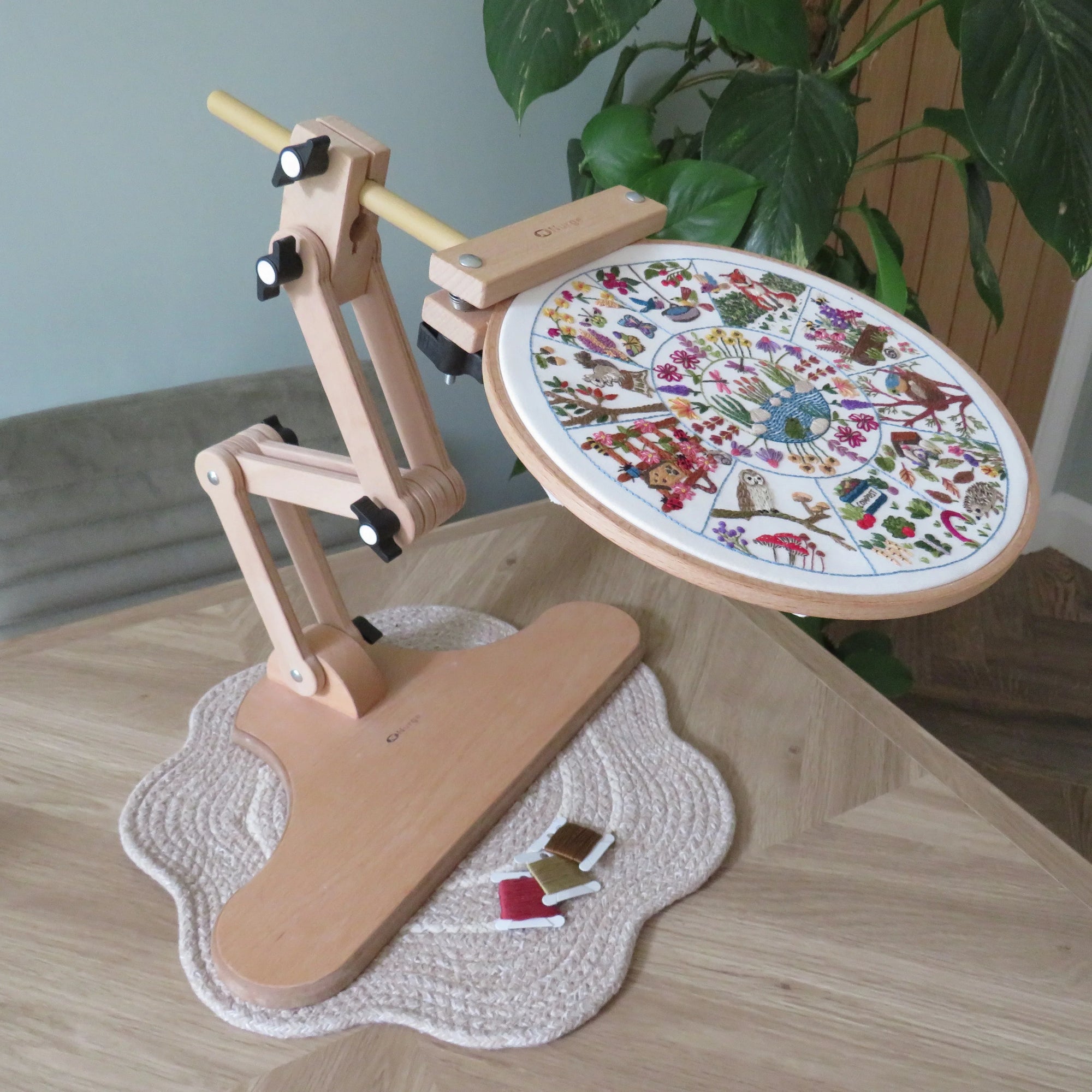 Wooden embroidery hoop stand with a colorful embroidery design on a wooden table.