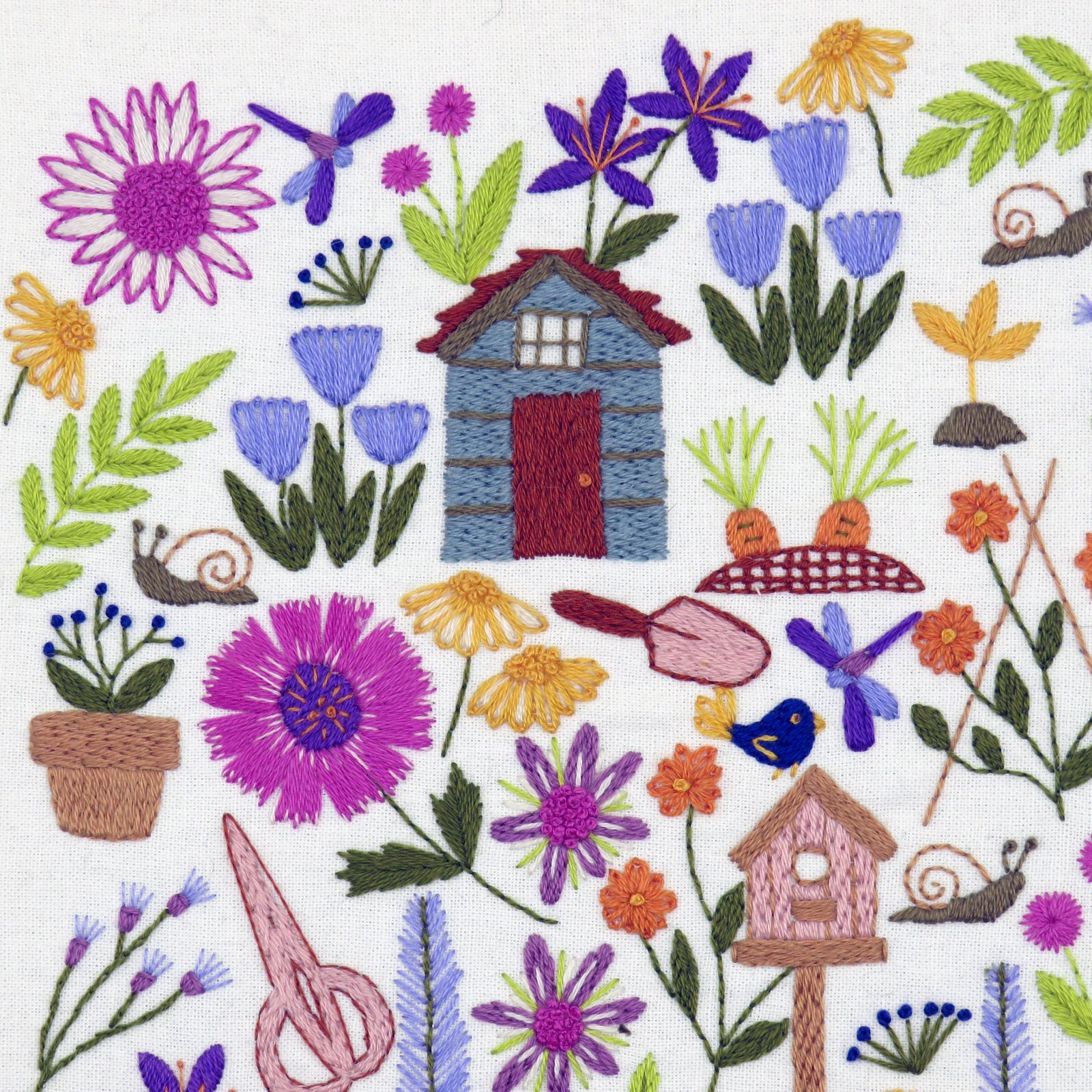 Embroidered design with flowers, a small house, and various elements on a white background