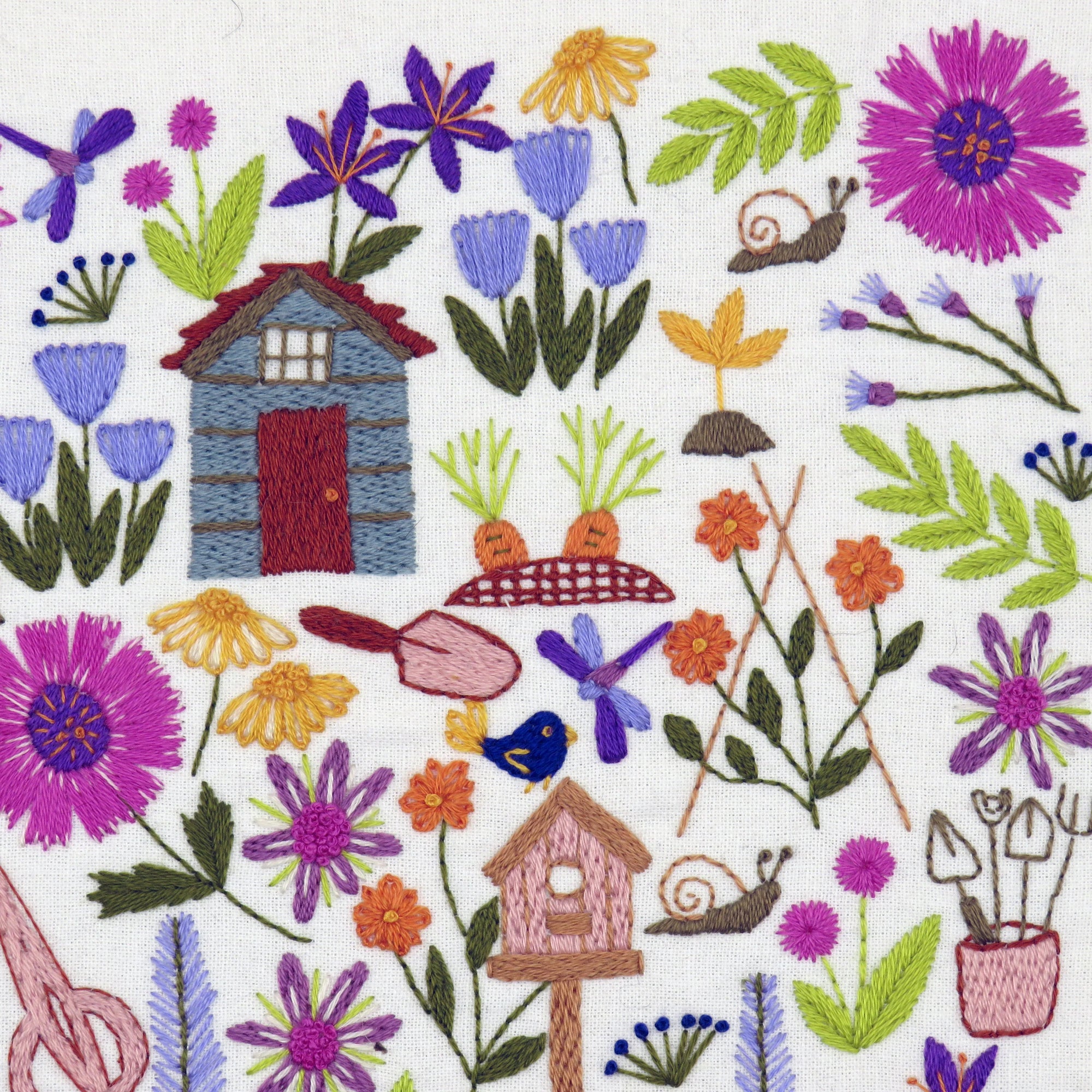 Embroidered design with flowers, a small house, and gardening tools on a white background.
