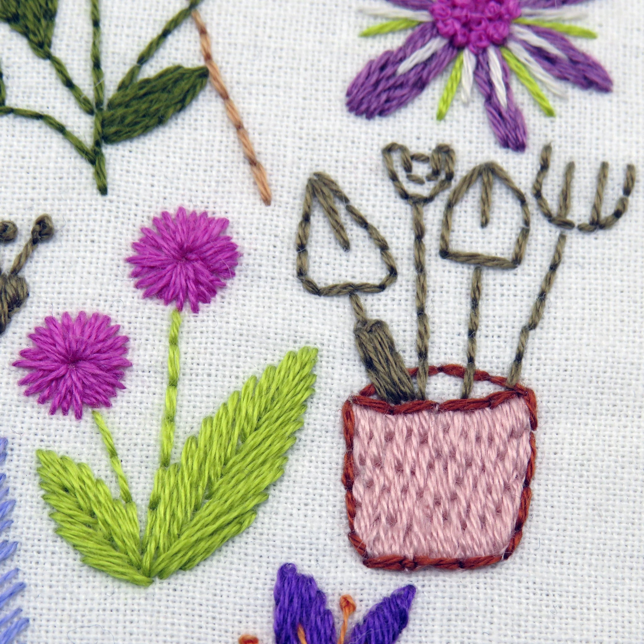 Embroidered design of flowers and gardening tools on fabric