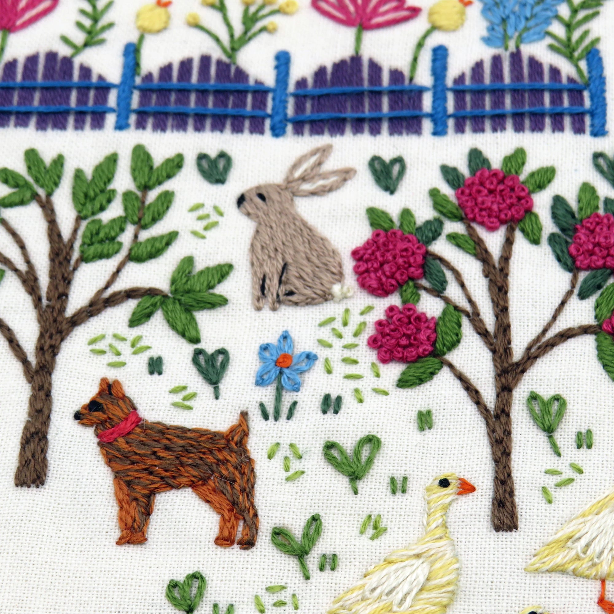 Embroidery design with a rabbit, dog, and duck in a garden setting.