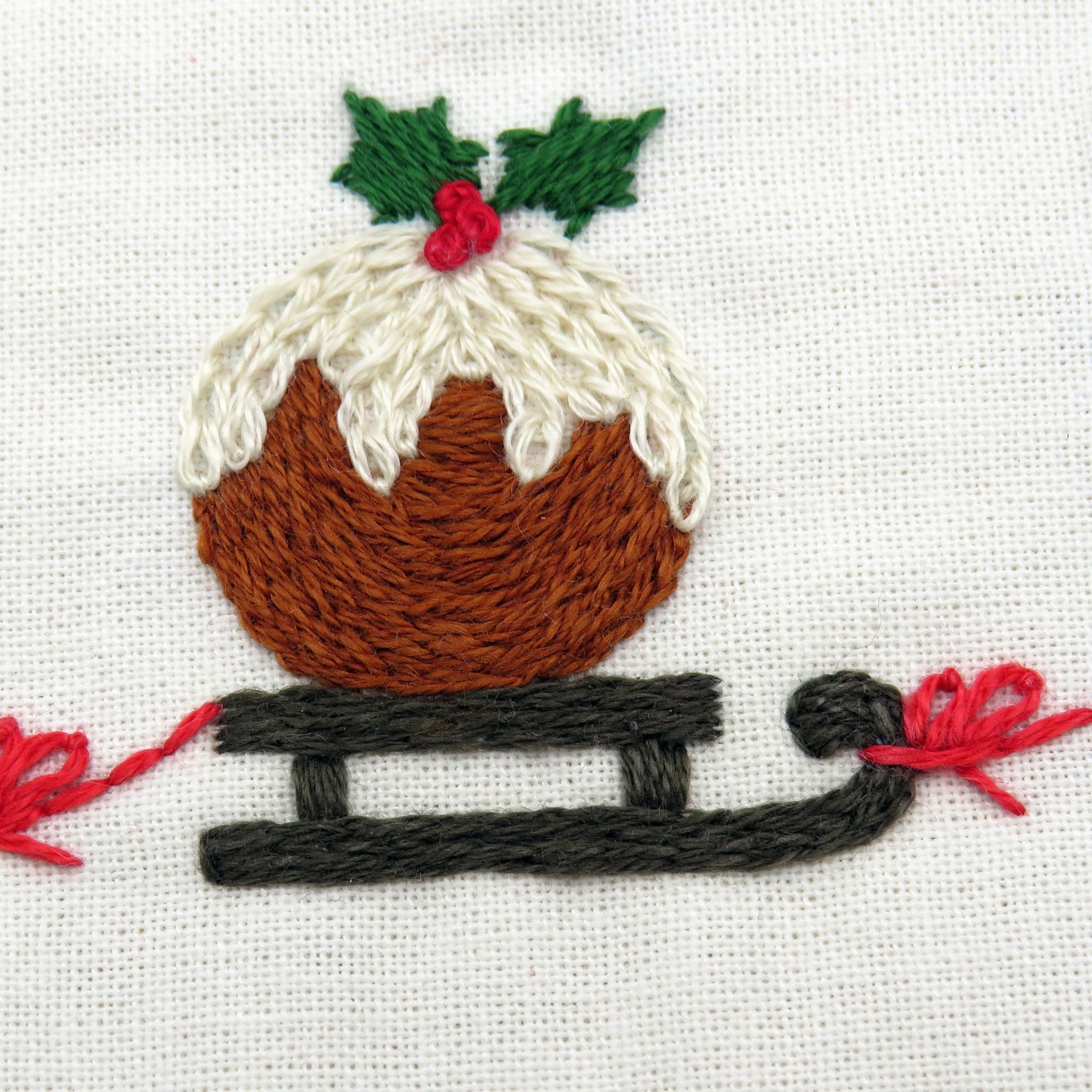 Embroidered design of a Christmas pudding on a white fabric background