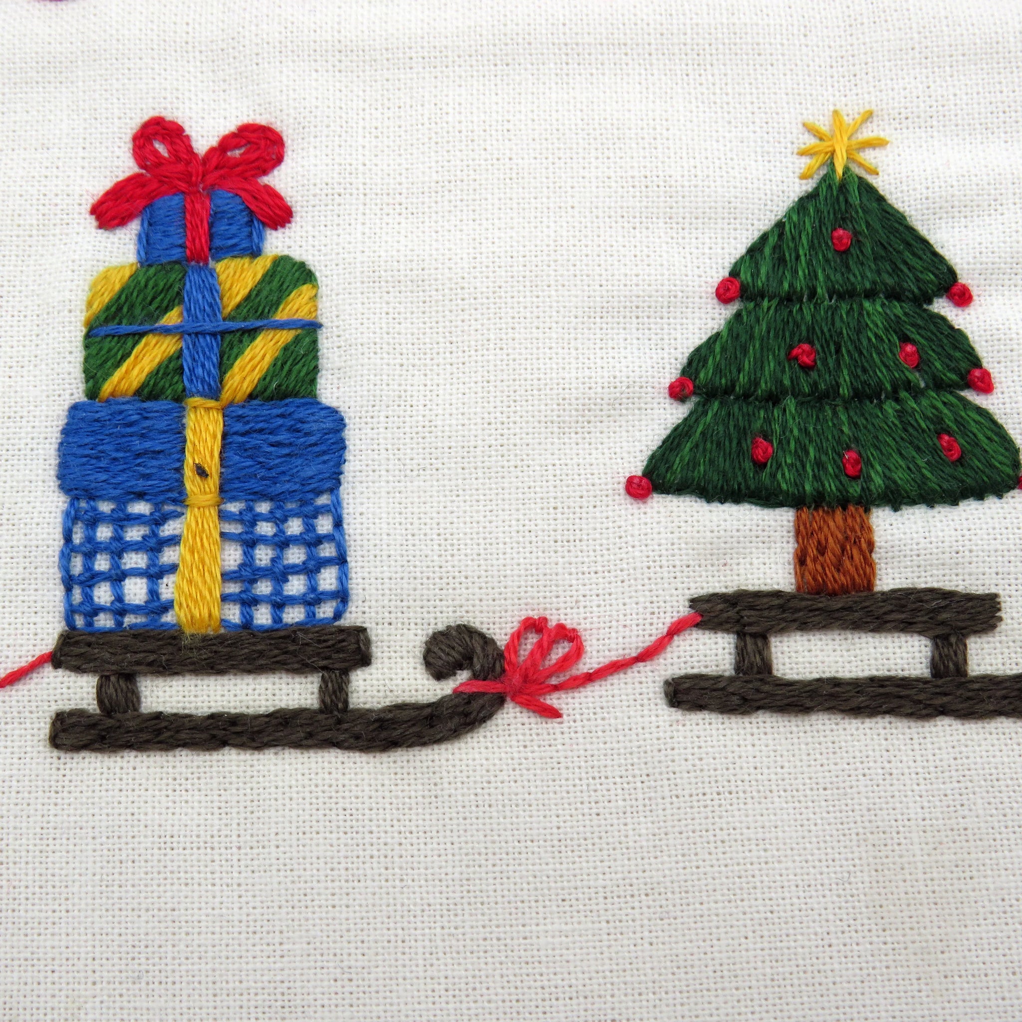 Embroidered design of a Christmas tree and presents on fabric.