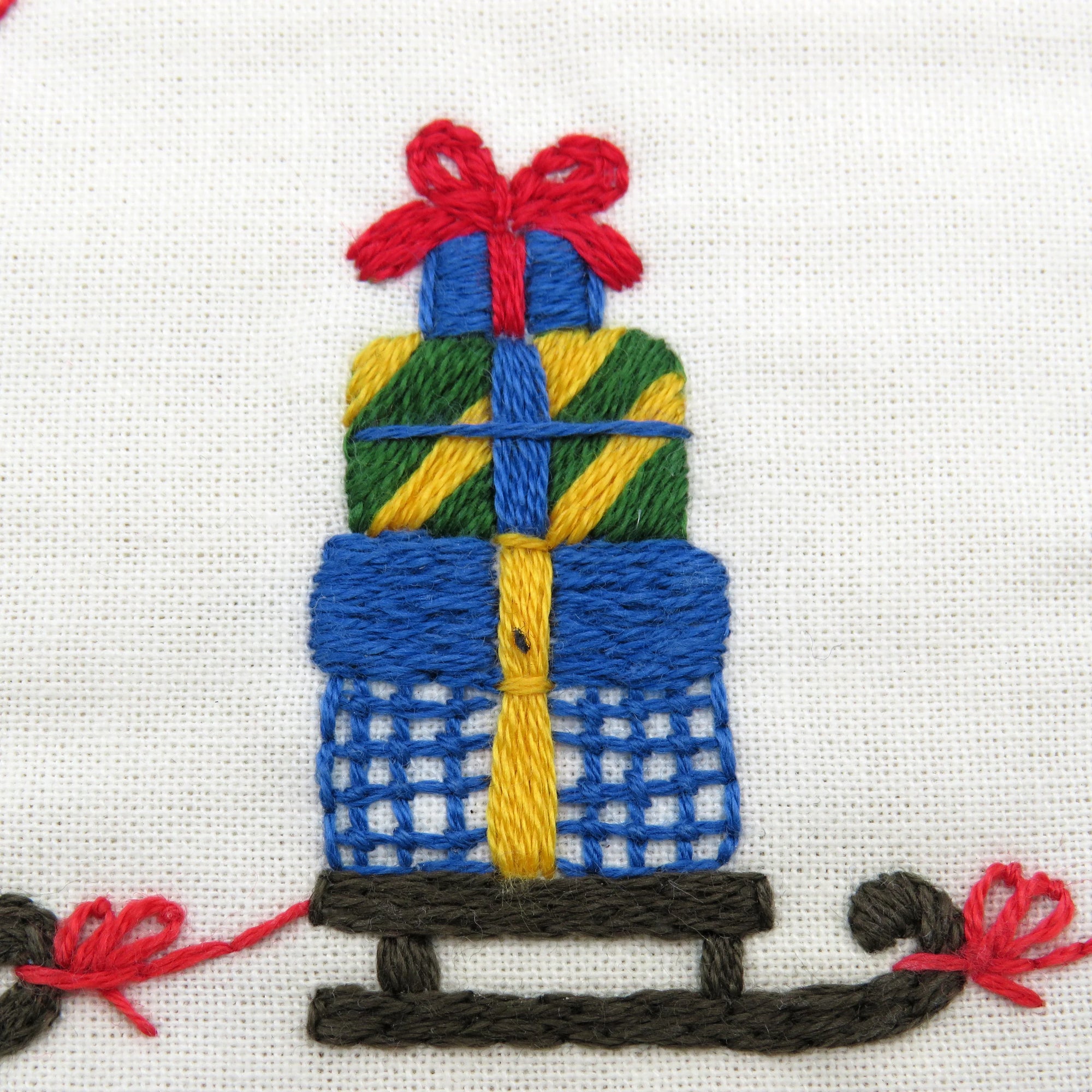 Embroidered design of a sled with wrapped presents on a white background