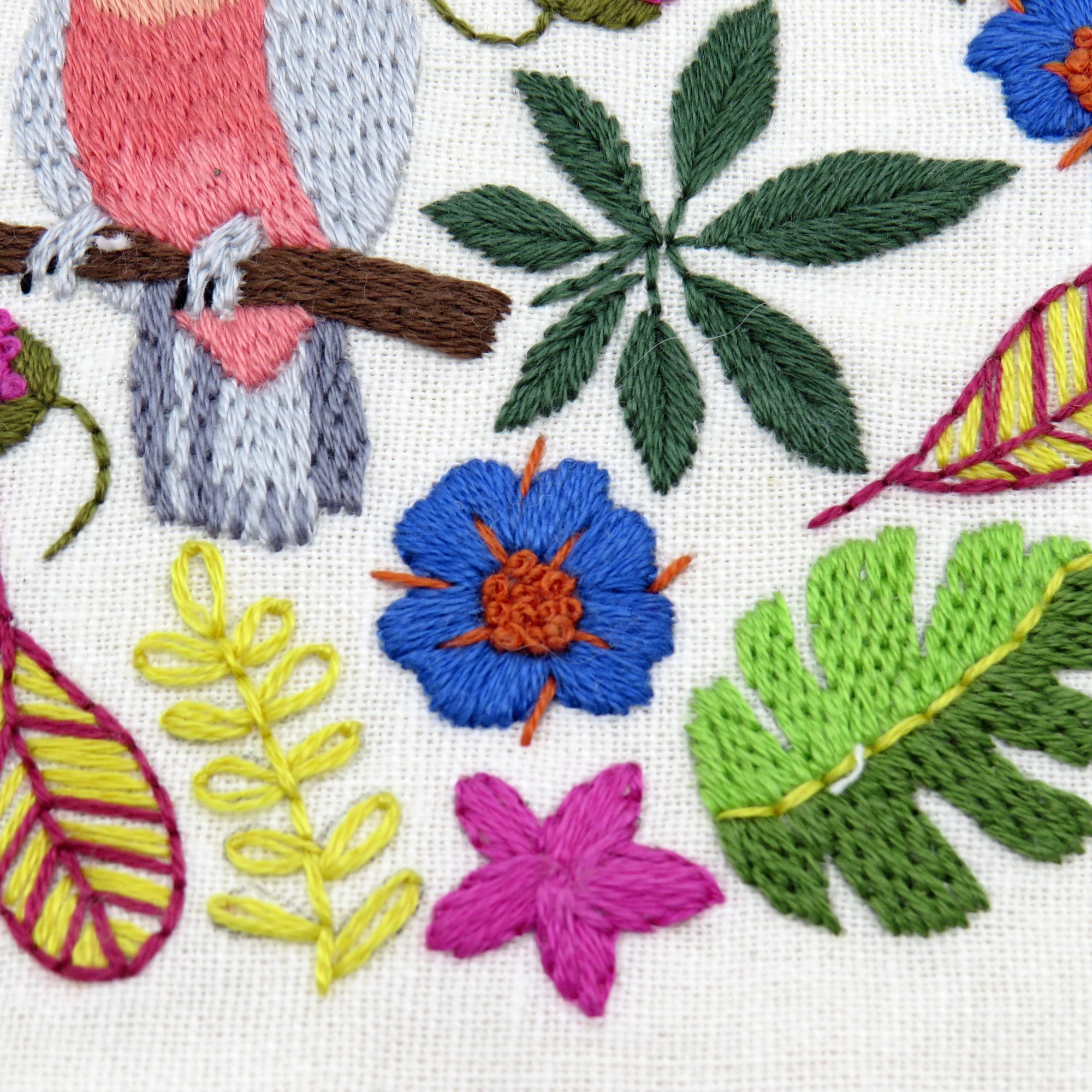 Embroidered design with flowers, leaves, and a bird on a white background