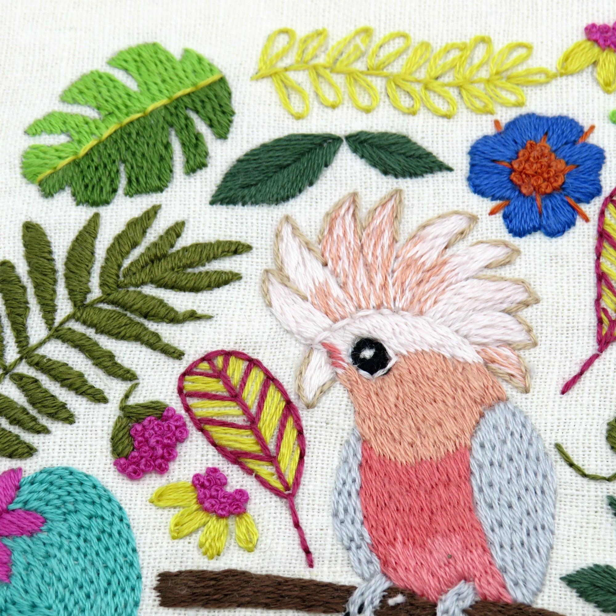 Embroidered parrot with floral and leaf patterns on a white background