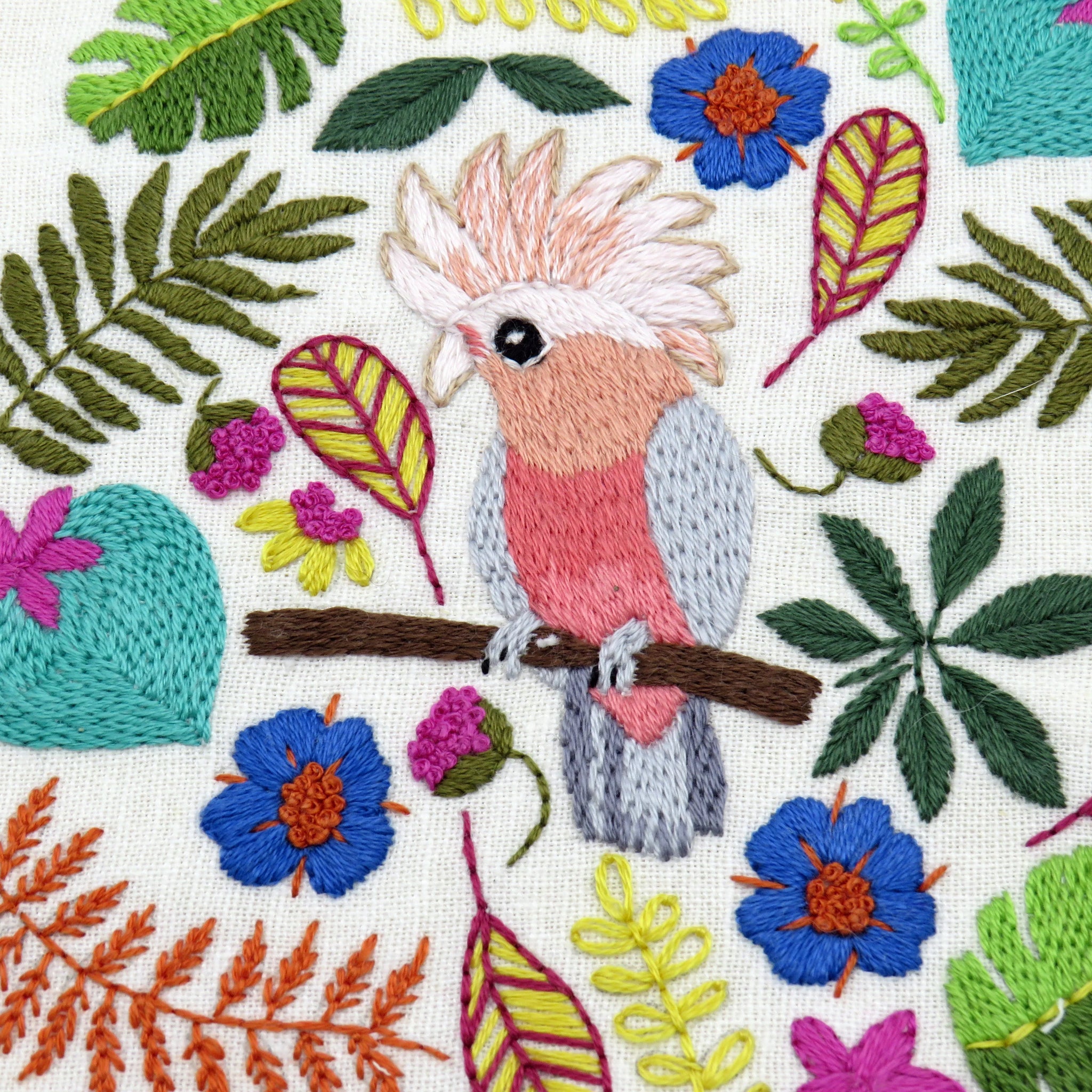 Embroidered design of a parrot and tropical leaves on fabric