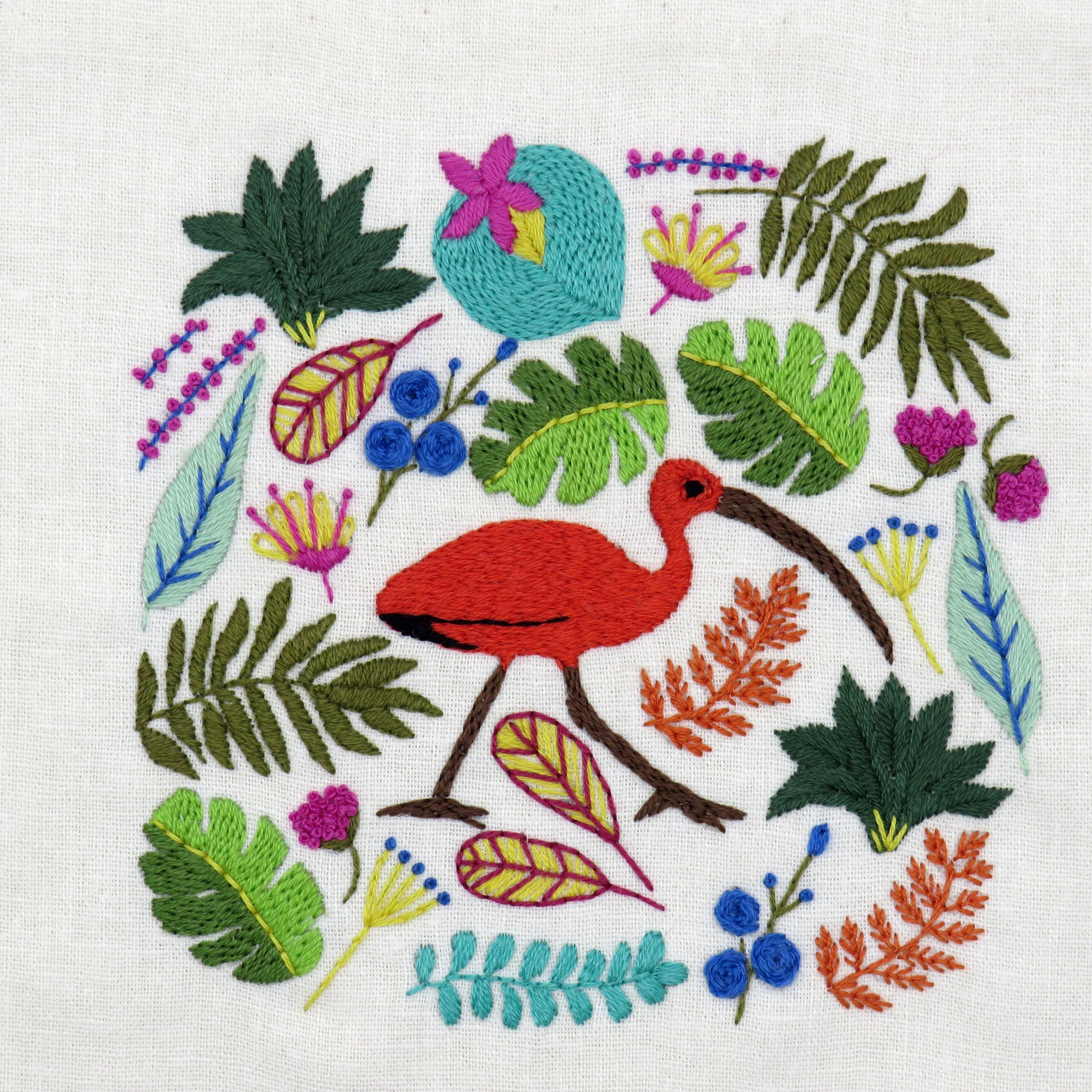 Embroidered design of a red bird surrounded by colorful leaves and flowers on a white background