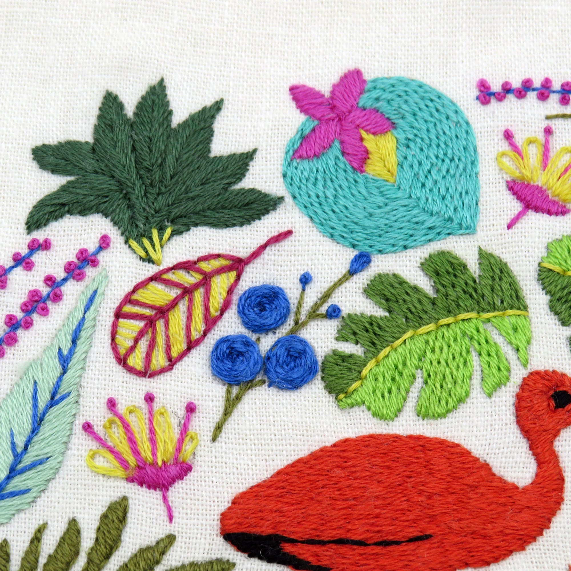 Embroidered design with colorful leaves, flowers, and a flamingo on a white background