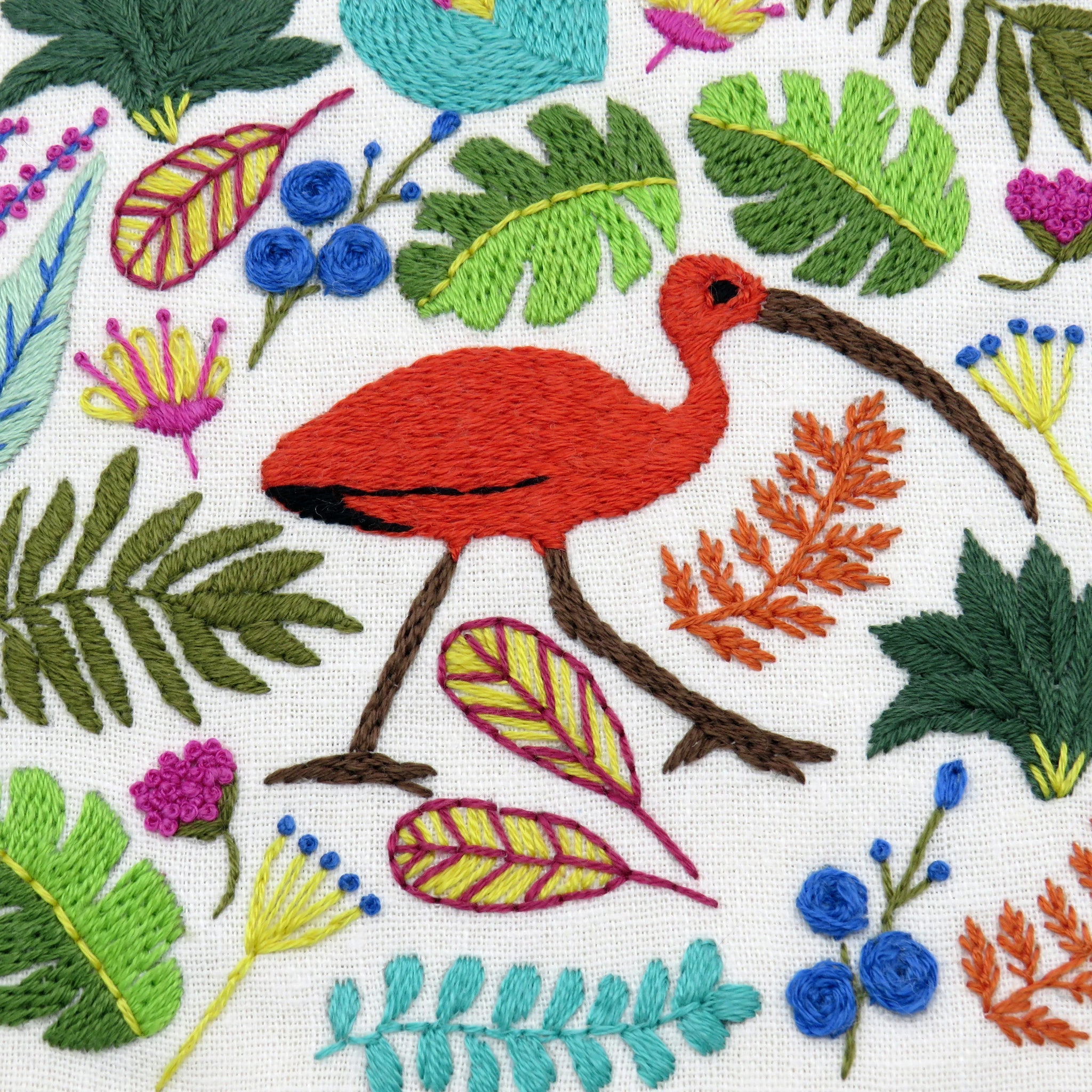 Embroidered design of a red bird with green leaves and flowers on a white background