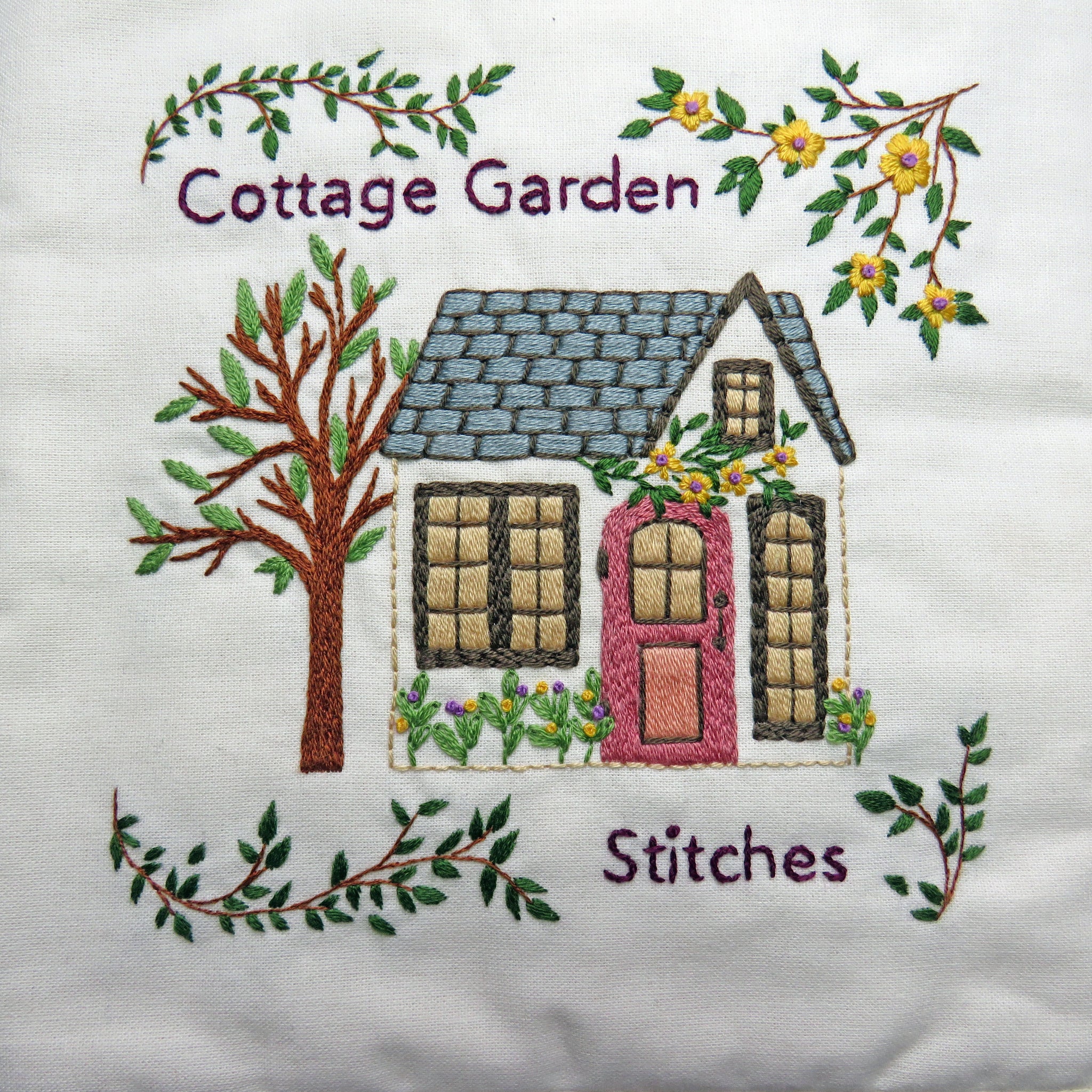 Embroidered design of a house with 'Cottage Garden Stitches' text on a white background